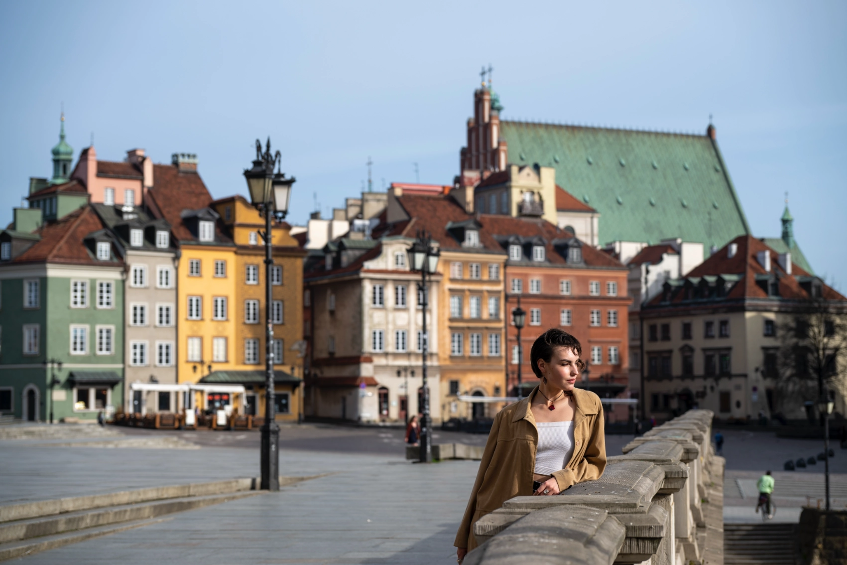 Warsaw Old Town, Poland A woman traveller stands on a bridge with colourful historic buildings in the background in Warsaw Old Town, Poland