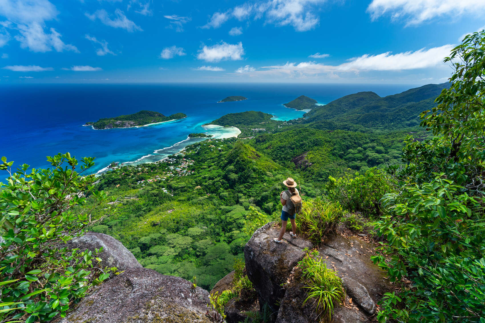 A woman standing atop a mountain in the Seychelles surveying the view below — amriphoto
