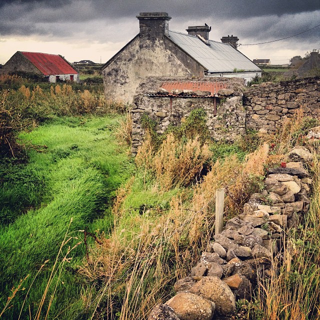 Country back roads of County Sligo, Ireland where the hills are dotted by old Irish farmhouses with rusted roofs and heavy stone walls.