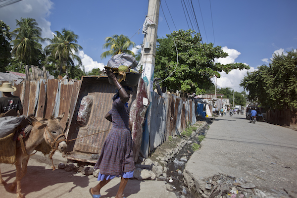 <p>Driving through the streets of Jacmel.</p> women walking with basin on her head in the street
