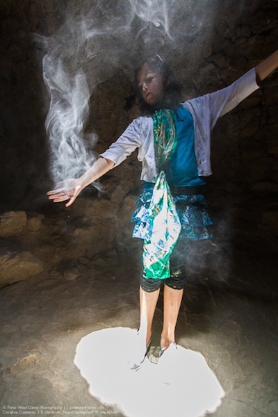 figure standing with smoke all around her caught in the light