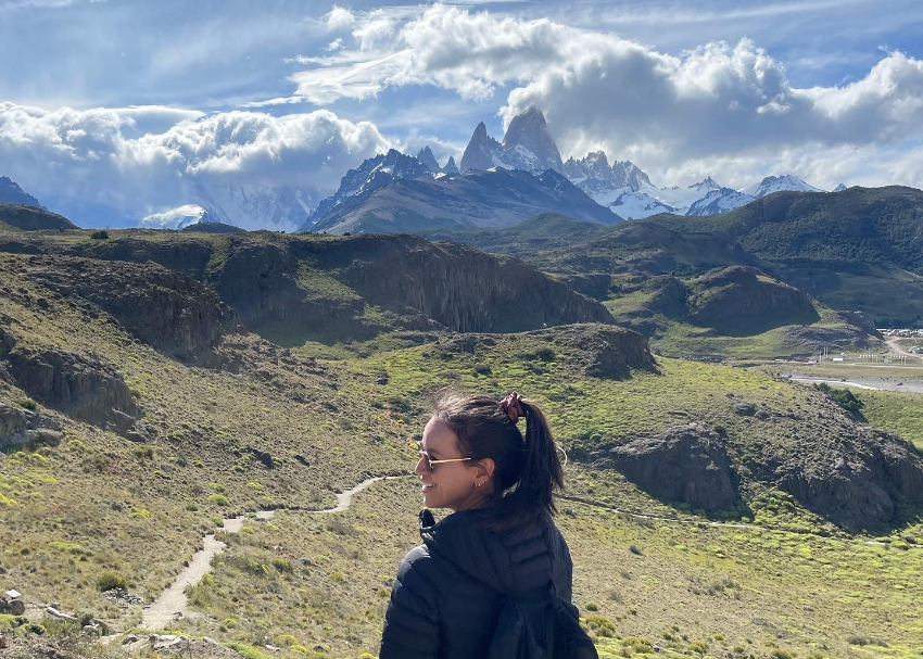 the familiar jagged peaks touch the clouds in the distance as writer Jessica Moy smiles as she walks ahead