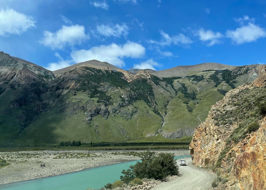 pristine green rocks border the turquoise blue river bed and the road