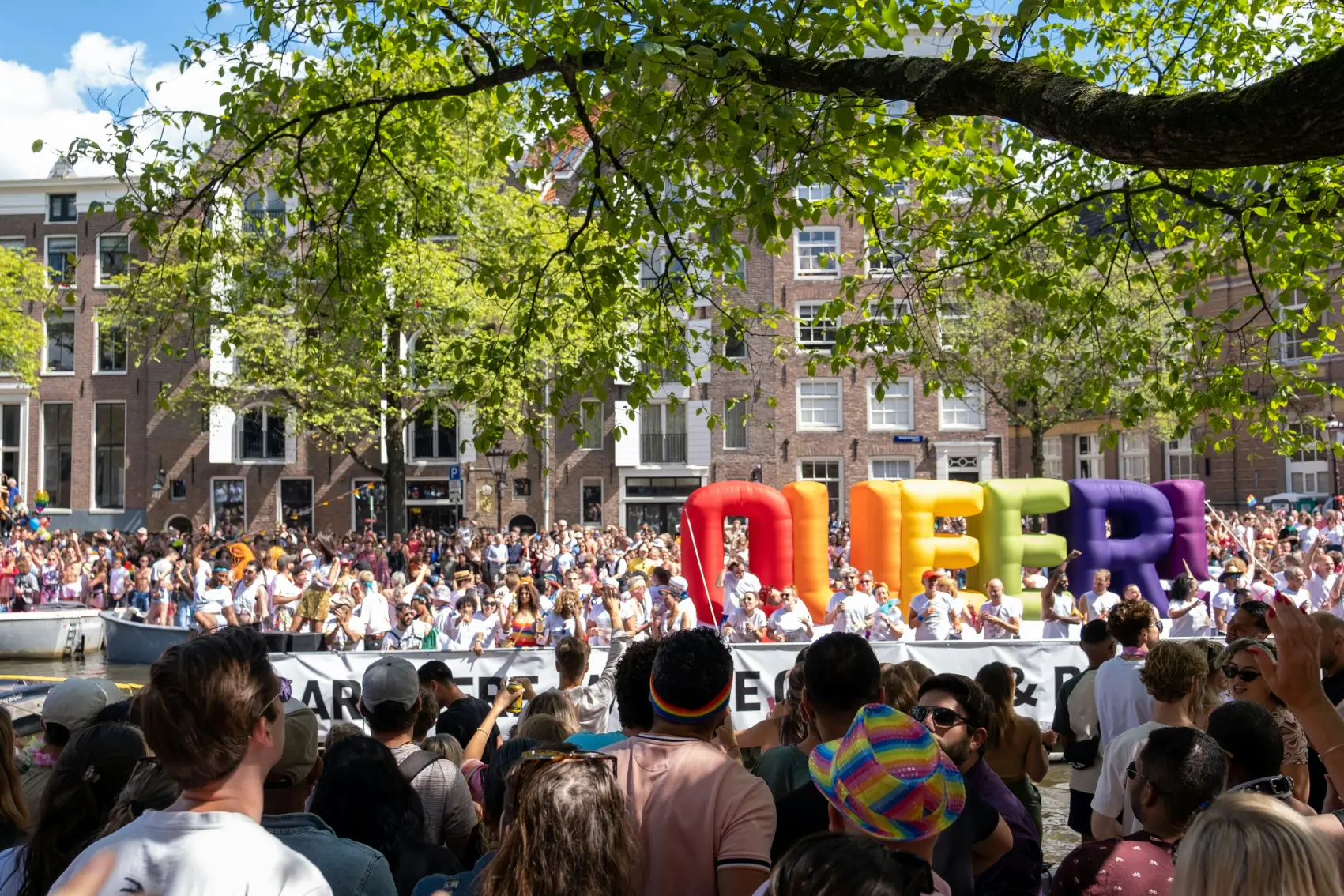 A giant rainbow balloon spelling queer stands out among the crowd of Amsterdam Pride revellers