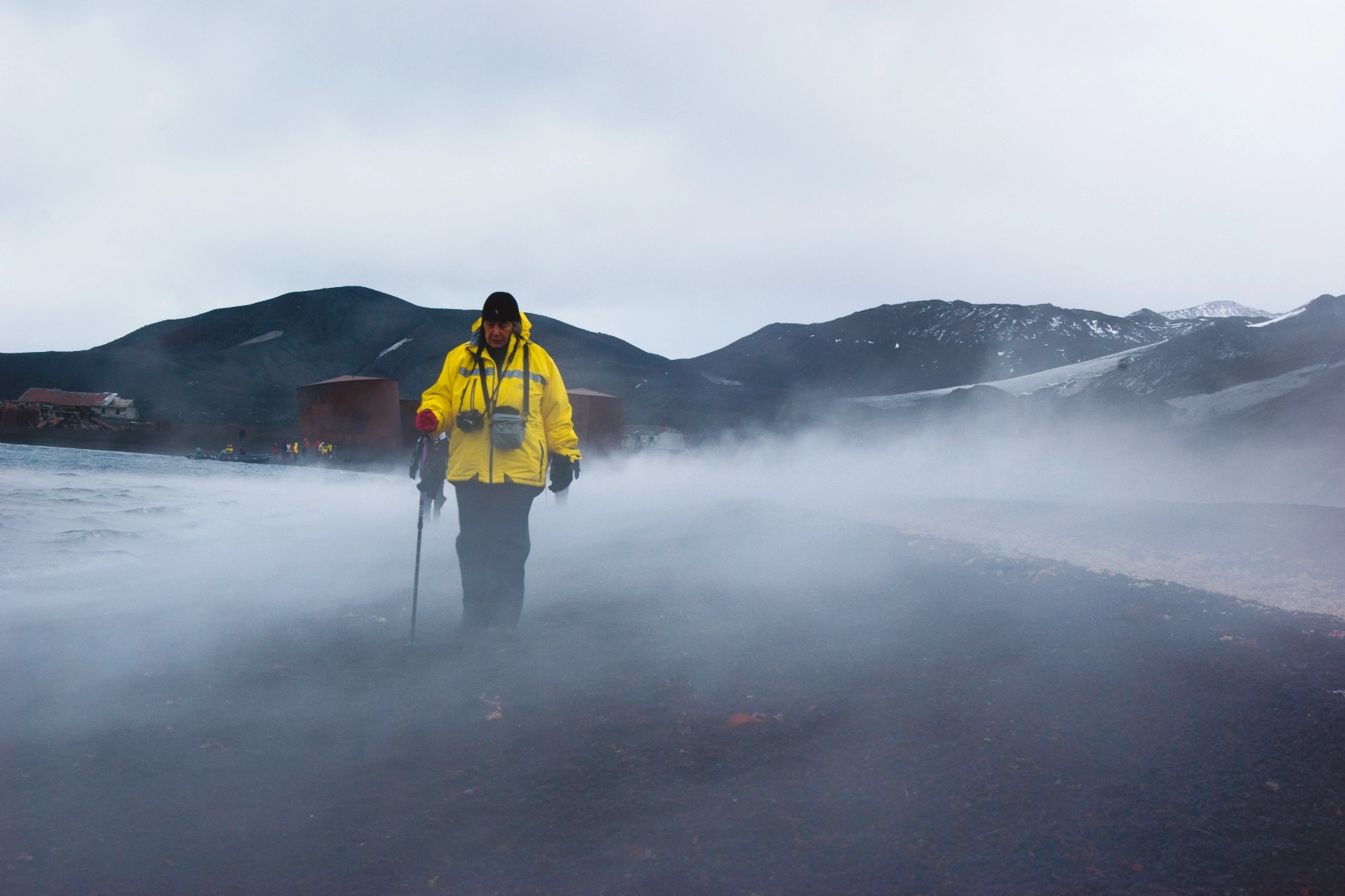 A traveller walks along the shore of a black-sand beach in Antarctica