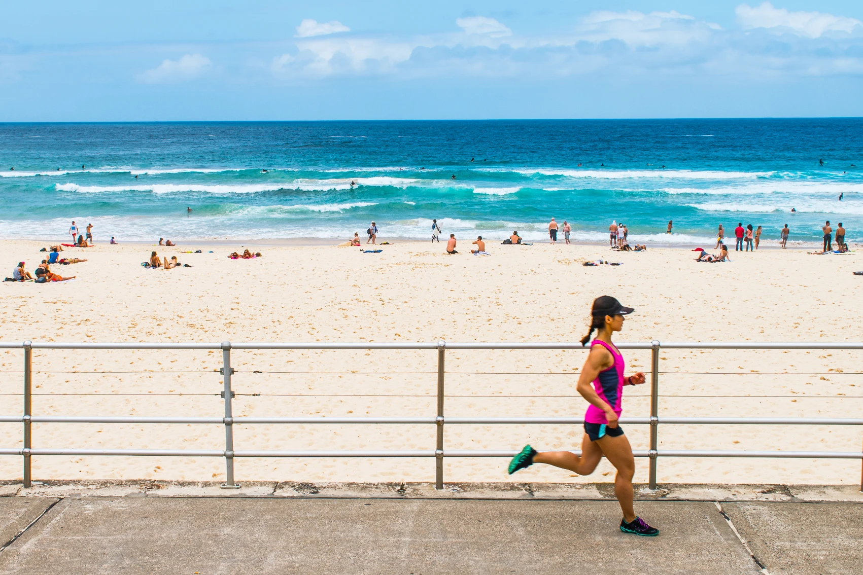 A woman runs along a paved sidewalk in front of Bondi Beach in Sydney, Australia