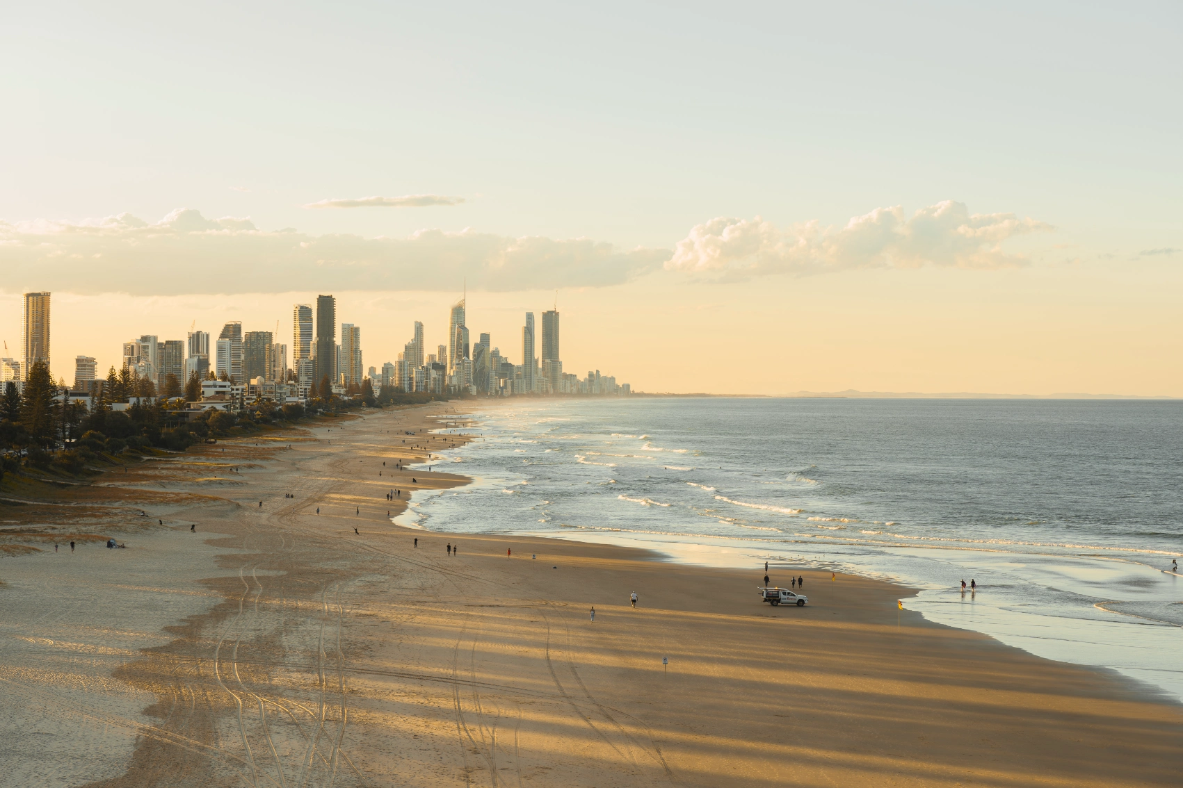 Elevated view of people walking on Burleigh Heads Beach, with skyscrapers rising in the background