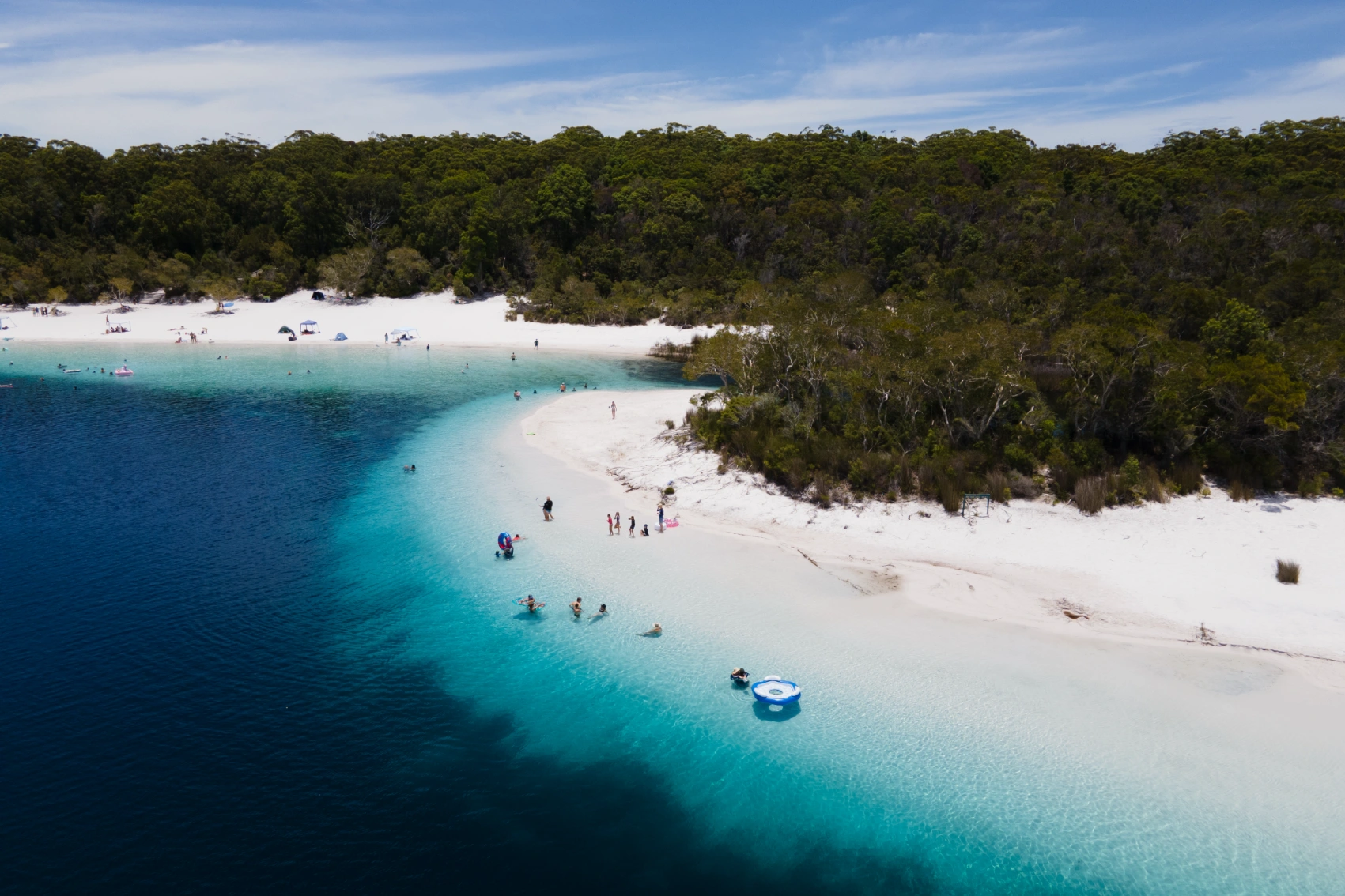 Aerial view of people next to the bright blue lake of Boorangoora in K'gari