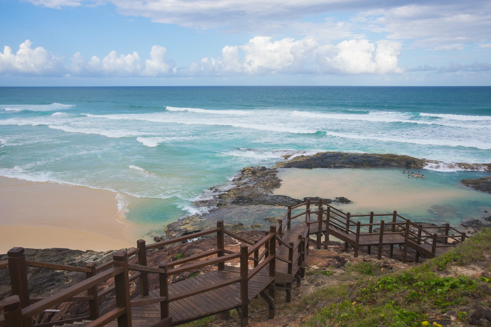 A boardwalk leads down to the Champagne Pools, where a group of people is swimming