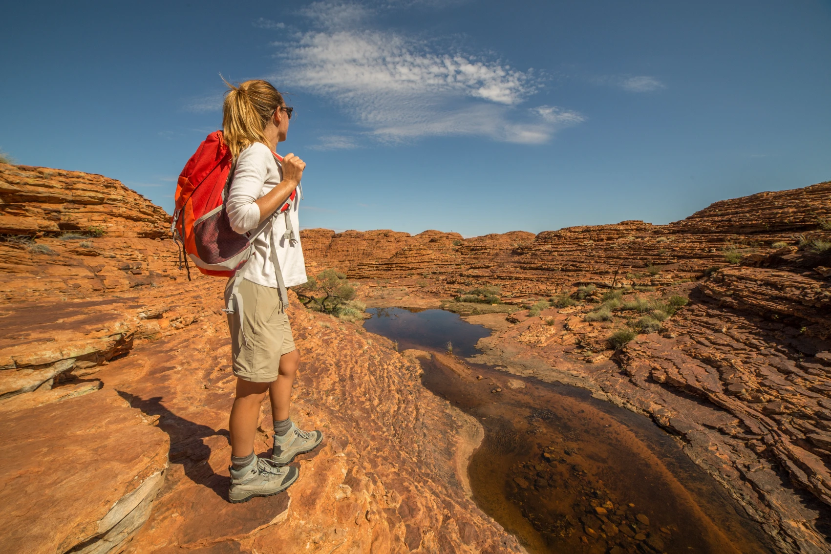 A hiker stands on the red rocks at the edge of Kings Canyon Australia