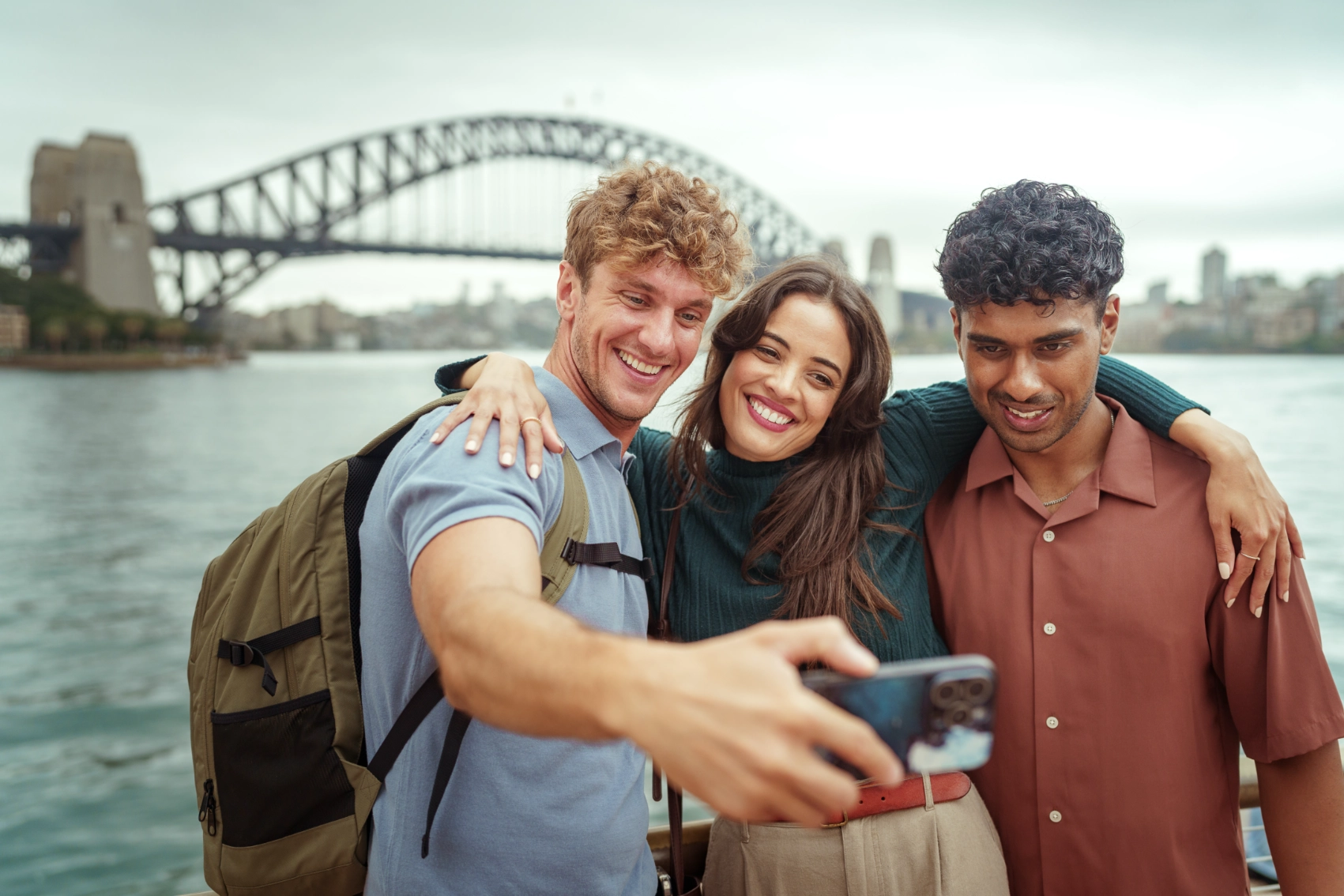 A group of friends takes a photo in front of the Sydney Harbour Bridge in Sydney, Australia