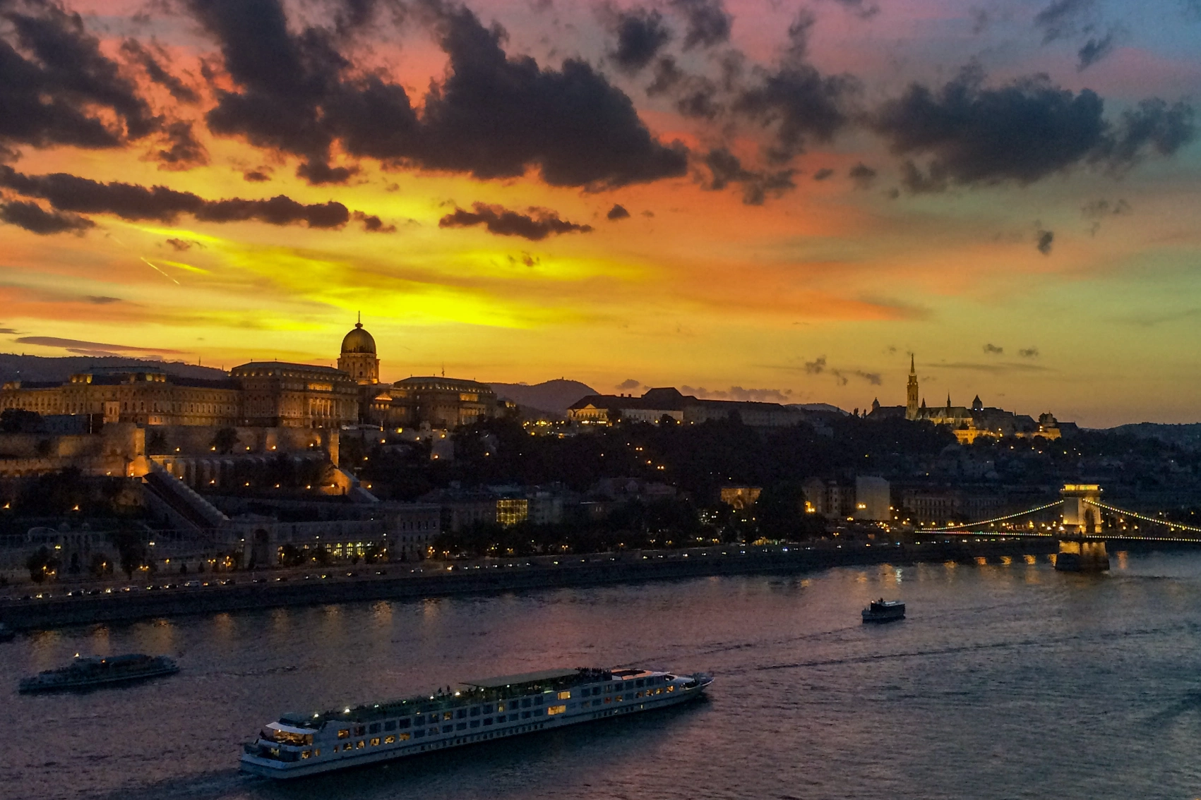 A boat cruises on the Danube River at sunset in Budapest, Hungary