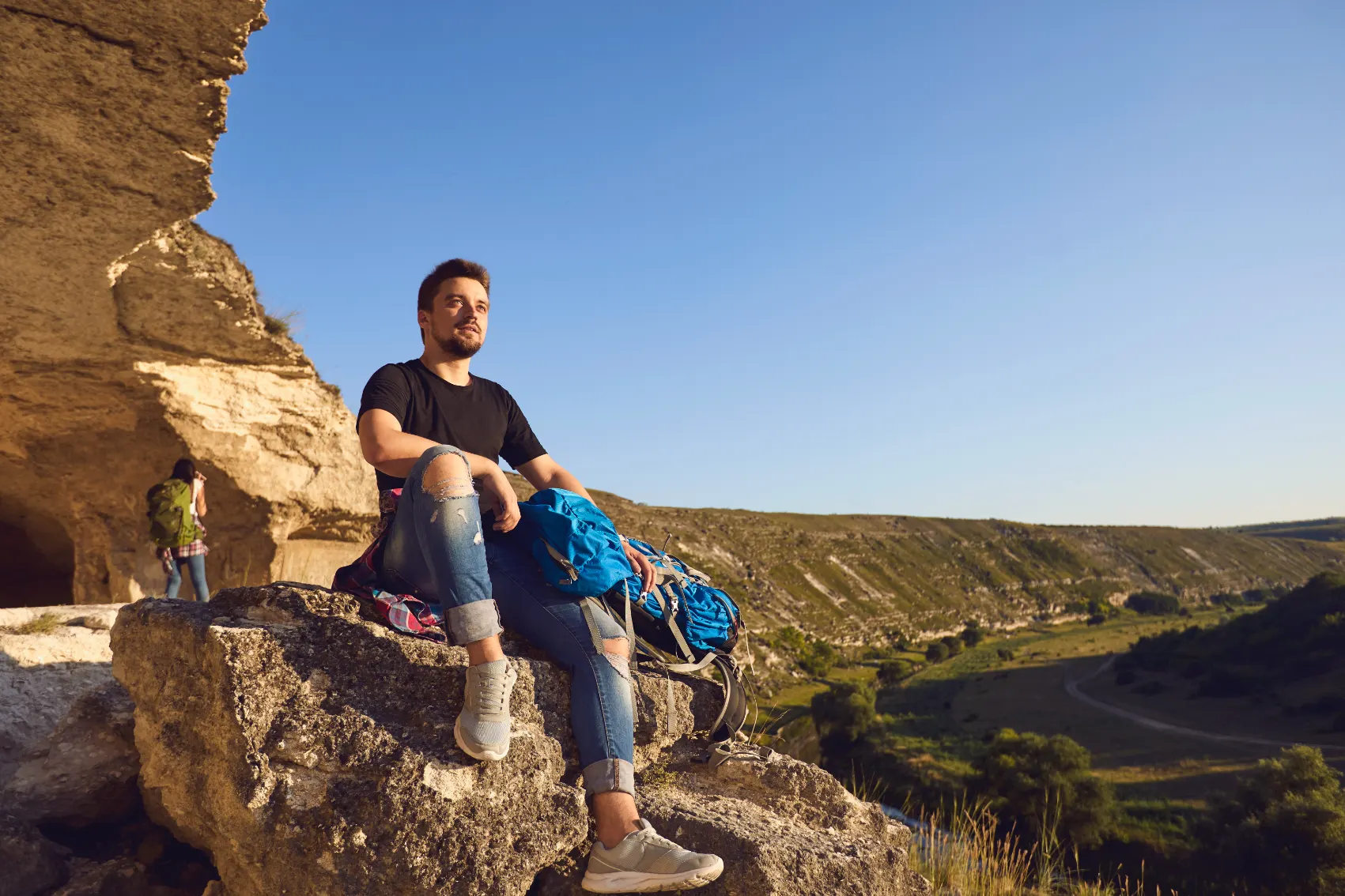 A young male traveller sits in front of cave openings at Old Orhei