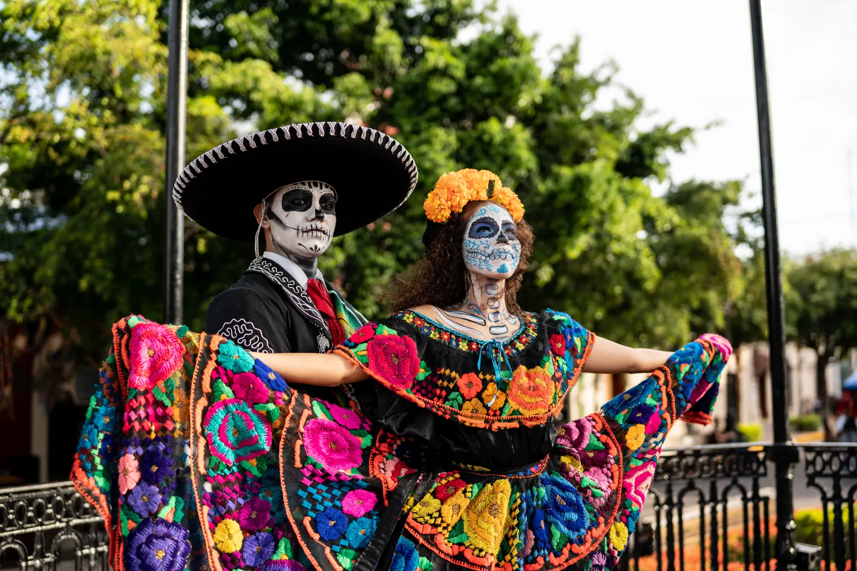 A man and woman in full sugar skull outfits celebrate in the park of Day of the Dead, Mexico