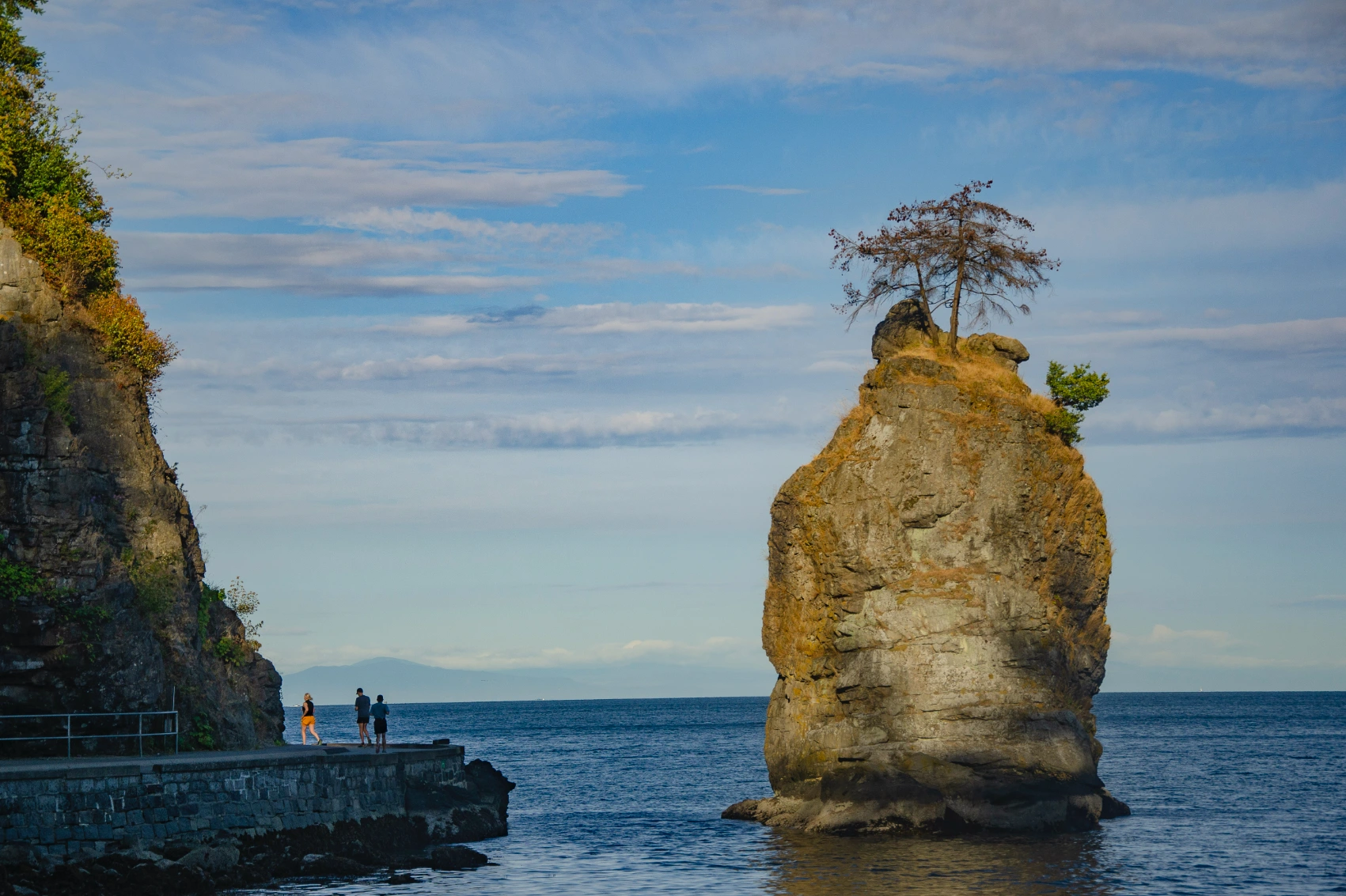 People walk on a trail along the Seawall in Stanley Park, Vancouver