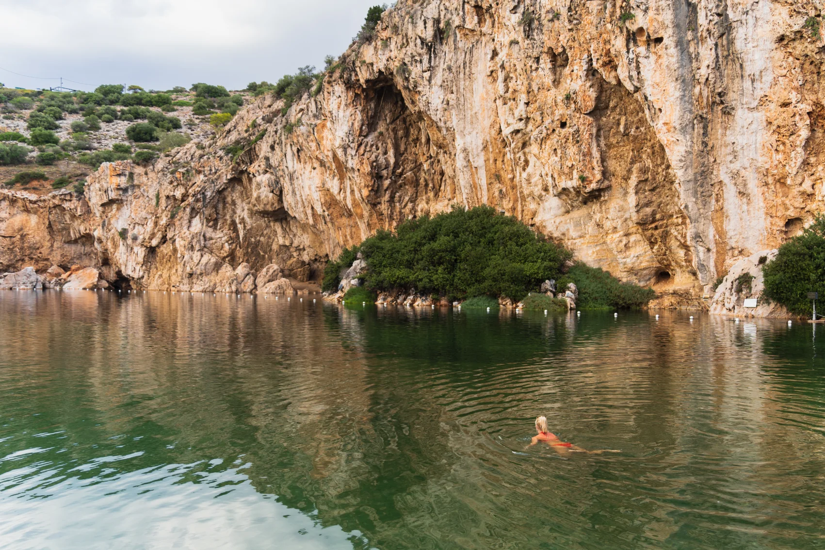 Lake Vouliagmeni, Greece A woman swims in the mineral thermal lake of Vouliagmeni in Greece