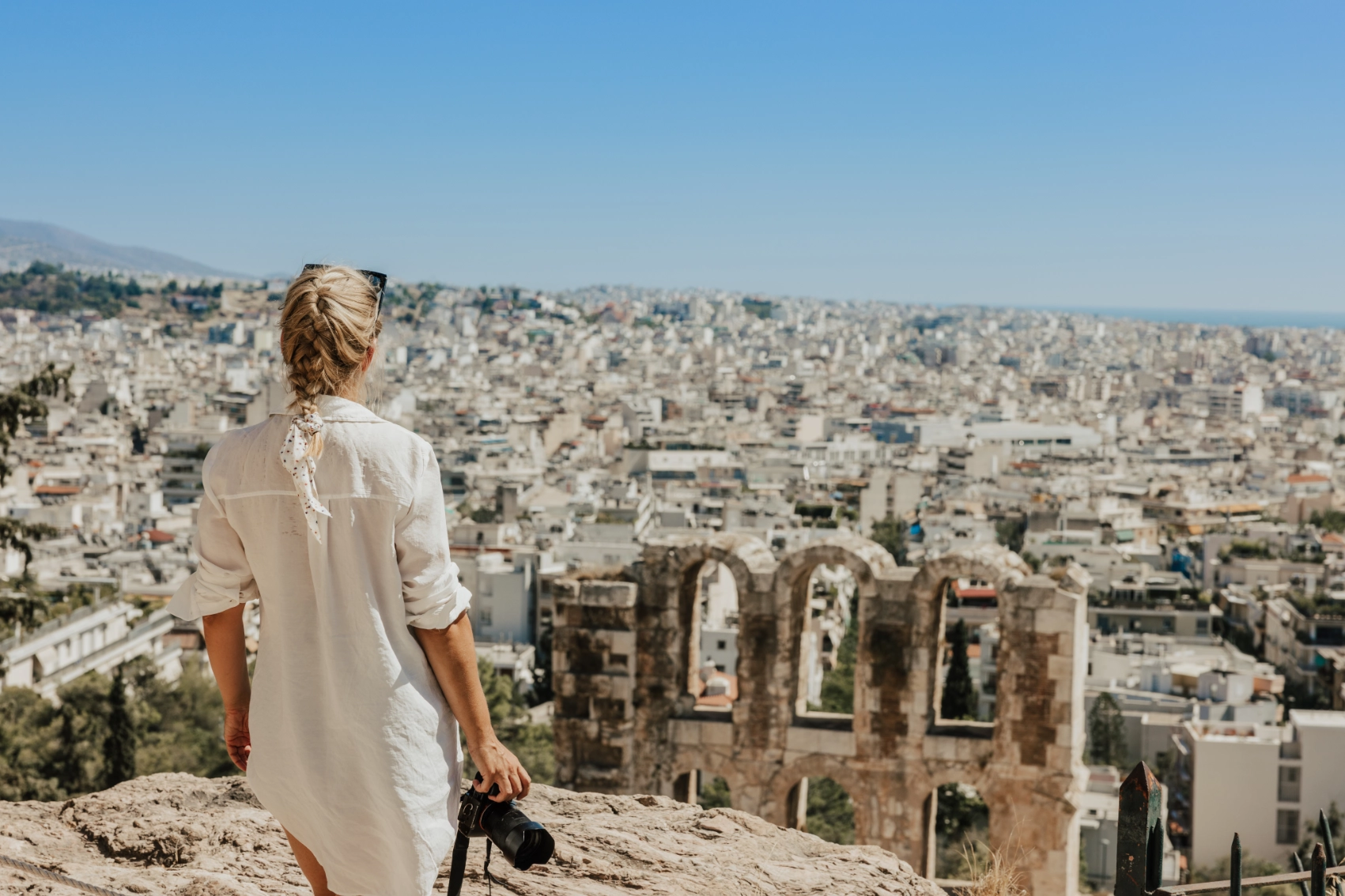 Odeon of Herodes Atticus, Athens A woman traveller with camera looks at the ancient theatre of Herodes Atticus against clear sky in Athens, Greece