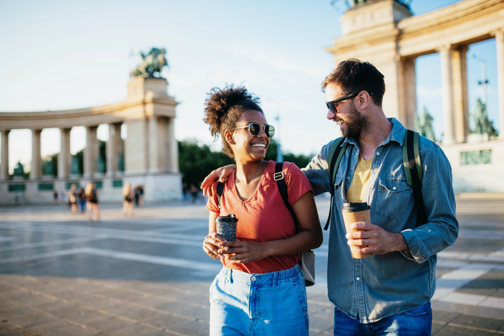 Budapest, Hungary A couple walks with coffees in a square in Budapest, Hungary