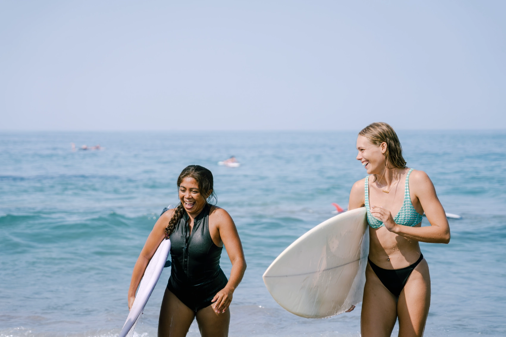 Surfing in Bali Two women with surfboards laugh as they walk on the beach in Bali