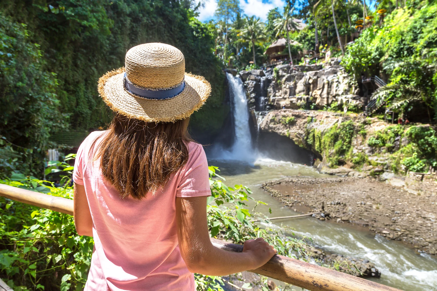 Tegenungan Waterfall, Bali A woman looks at Tegenungan Waterfall, Bali, from behind a fence