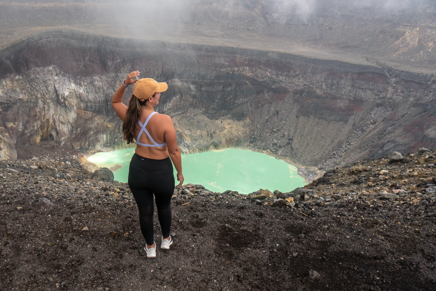 Santa Ana Volcano hike, El Salvador A woman hiker stands in front of the large water-filled crater of Santa Ana Volcano