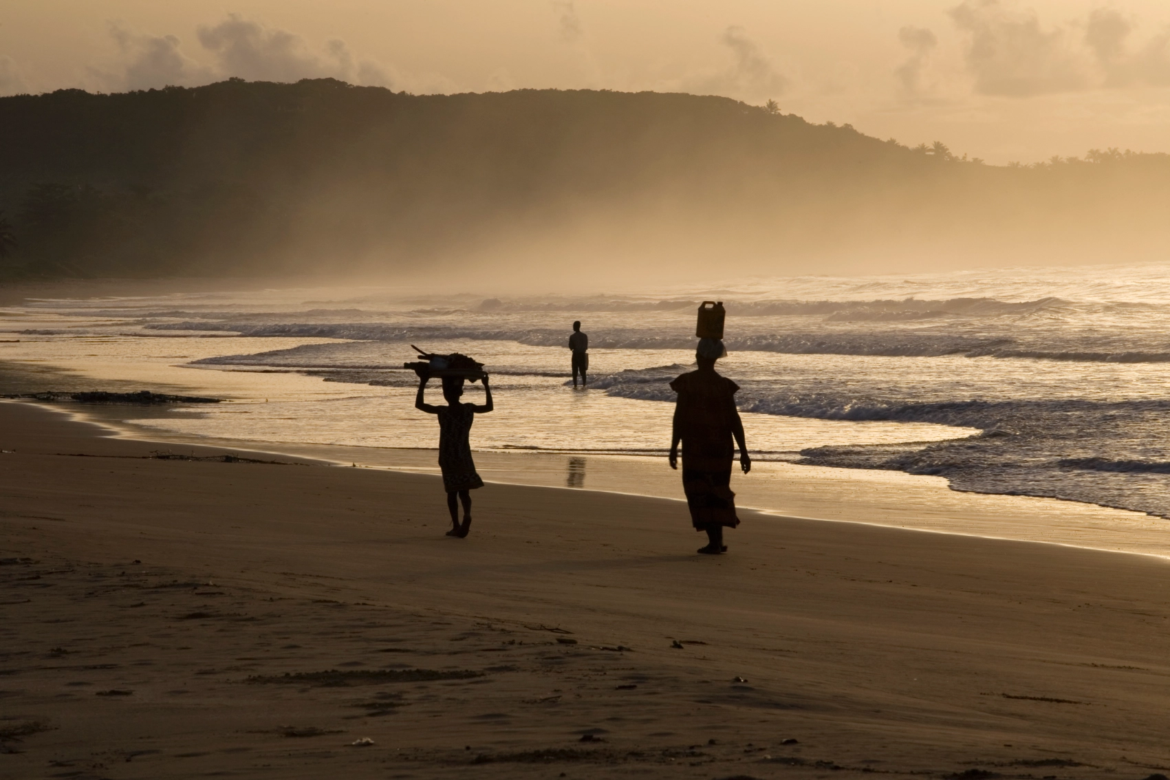 Busua Beach, Ghana People in silhouette walk along Busua Beach in Ghana at sunset