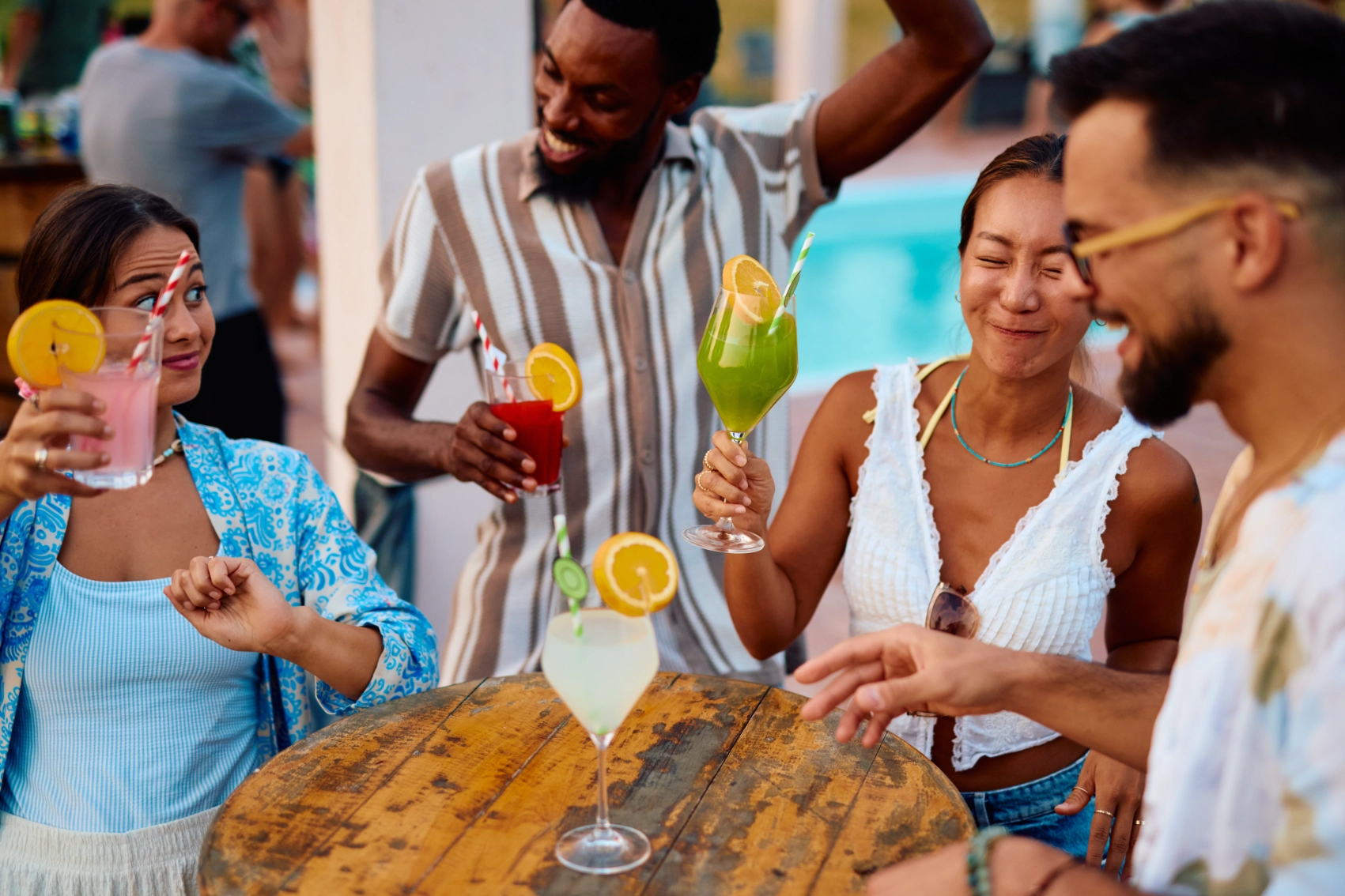Four friends hold drinks around a table in Mykonos, Greece