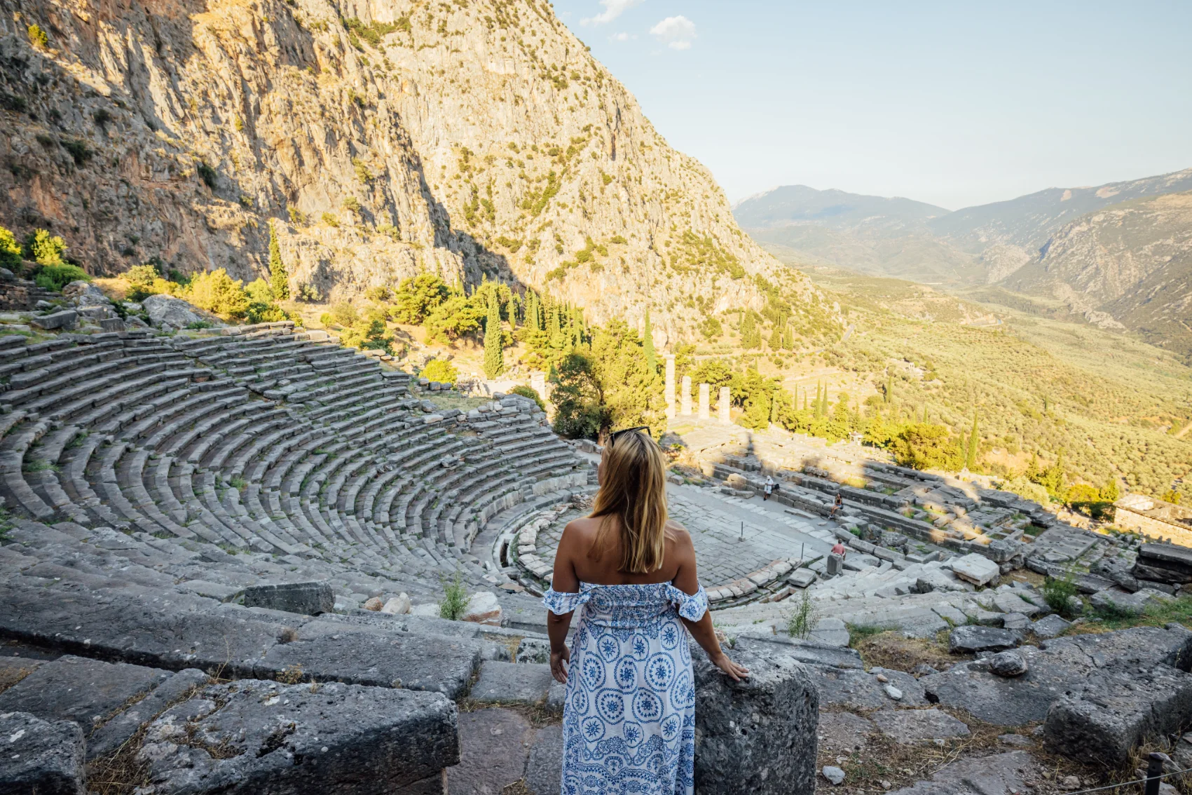 Temple of Apollo, Delphi A woman stands above the ruins of a Greek amphitheatre at the Temple of Apollo in Delphi