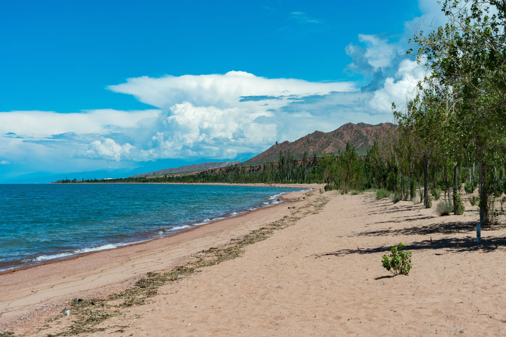 Blue water laps on a sandy beach at Issyk-Köl, Kyrgyzstan