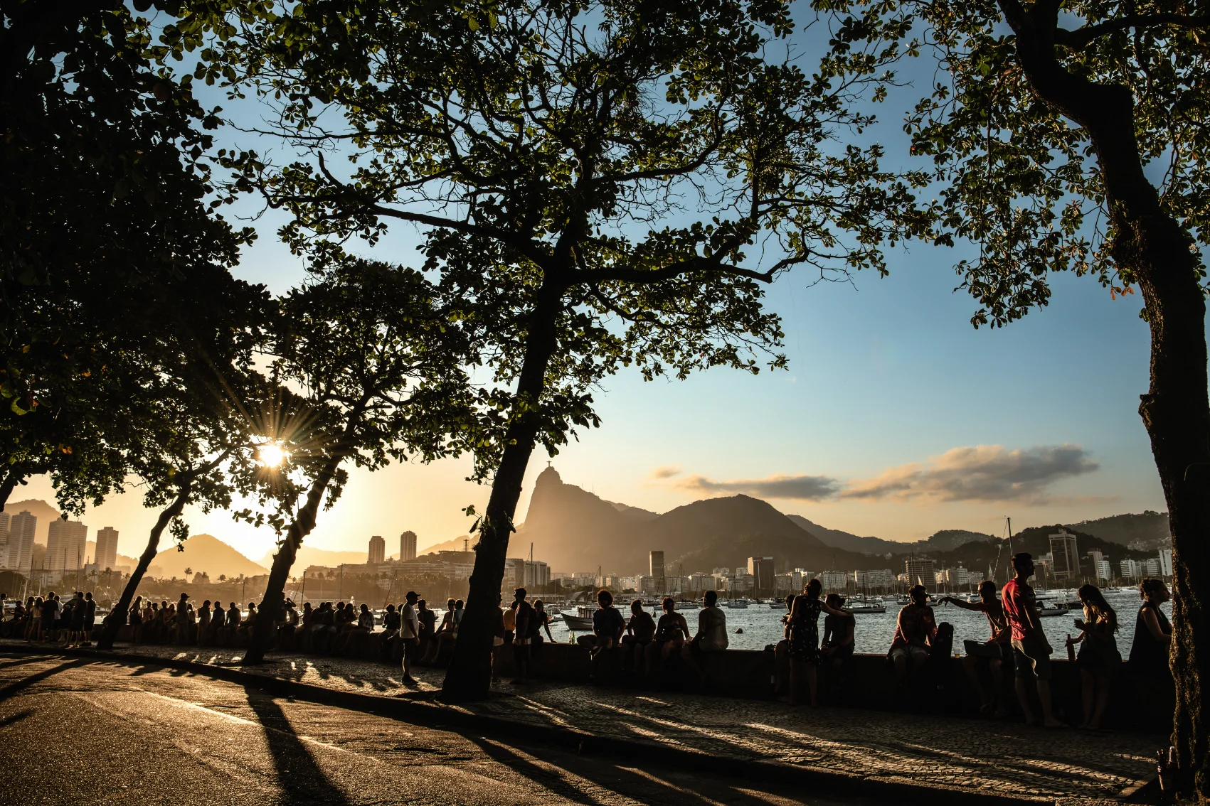 People sit on the wall at Mureta da Urca to watch the sunset in Rio de Janiero, Brazil