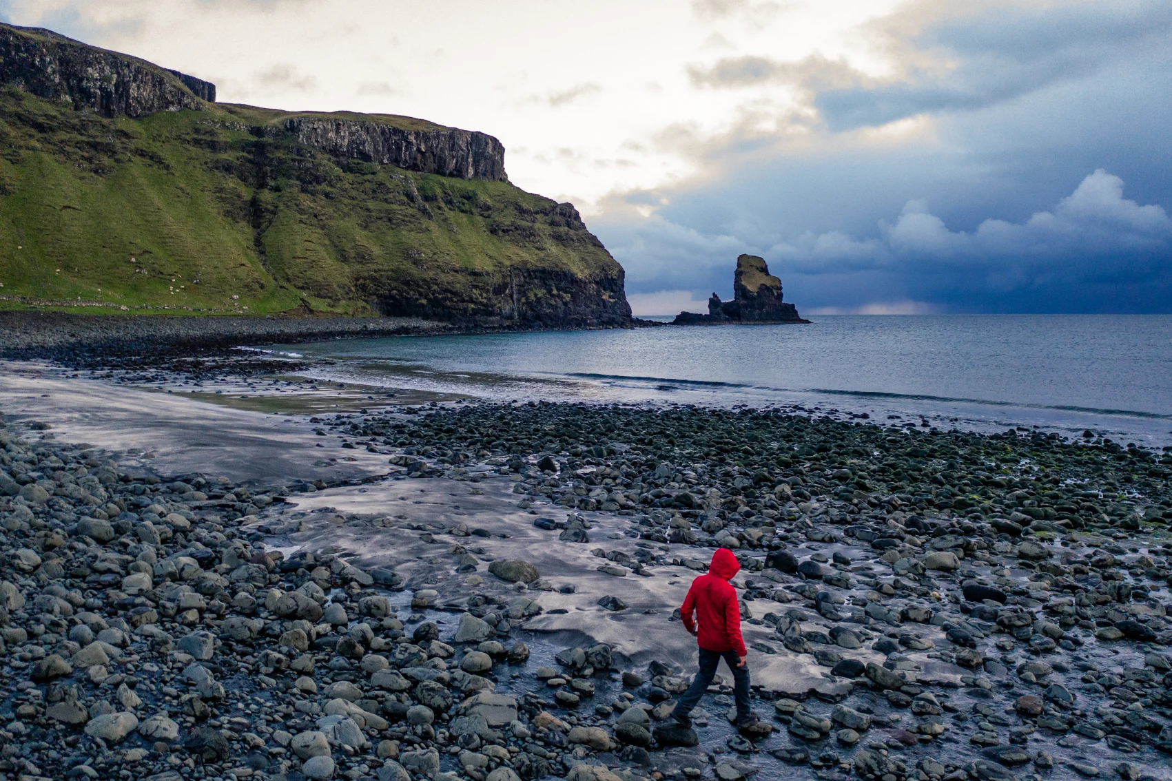 A man walks near the water of Talisker Bay, Scotland