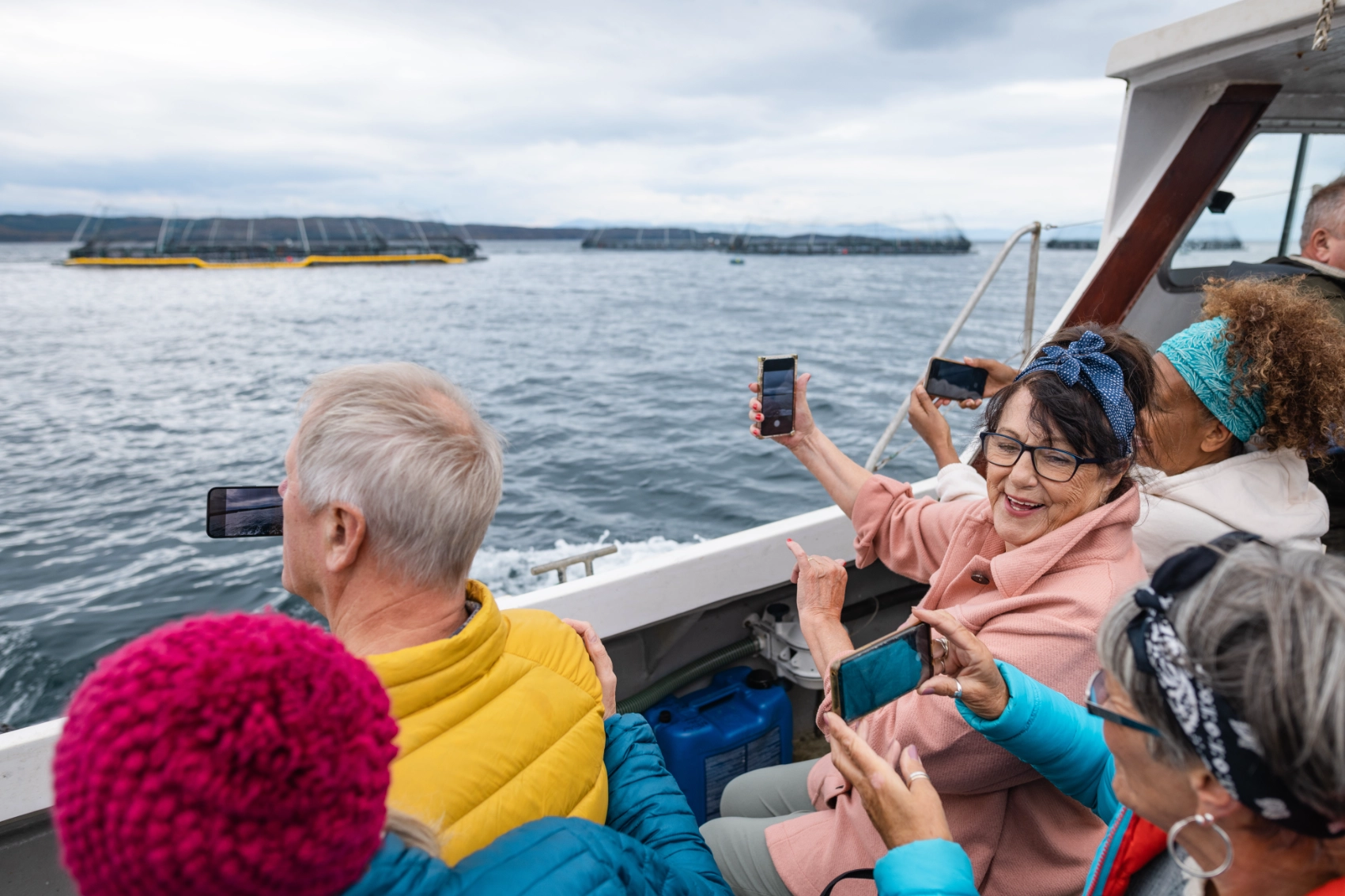 A group of travellers takes photos from the side of a boat in Scotland