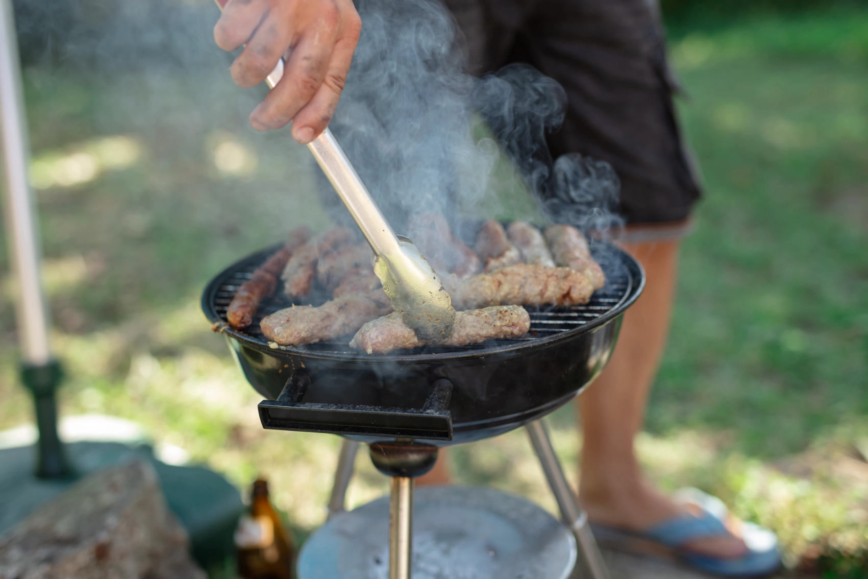 A man grills ćevapi sausages outdoors
