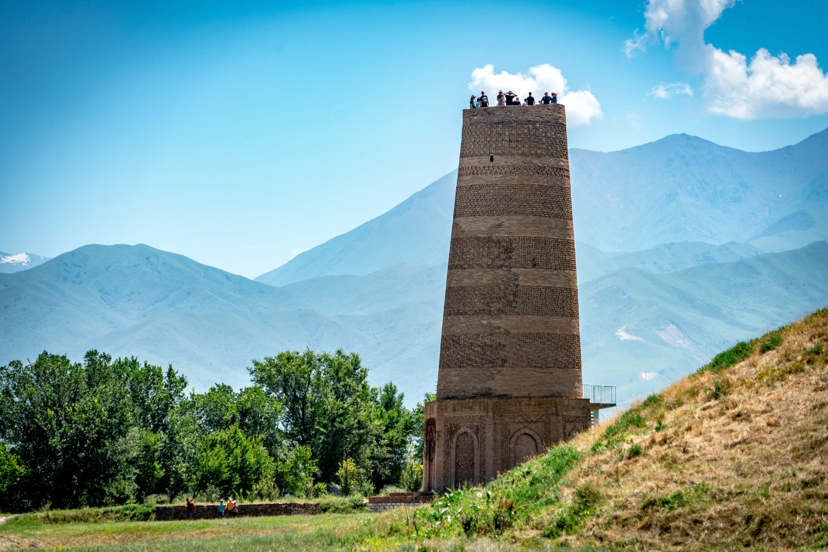 Burana Tower sits in a lush meadow with mountains in the background