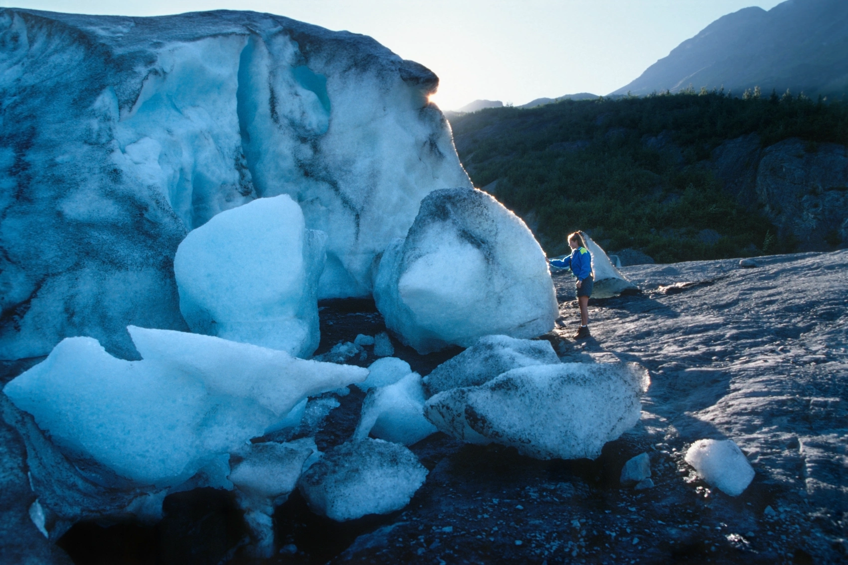 A woman traveller touches the remnants of Exit Glacier while hiking in Alaska