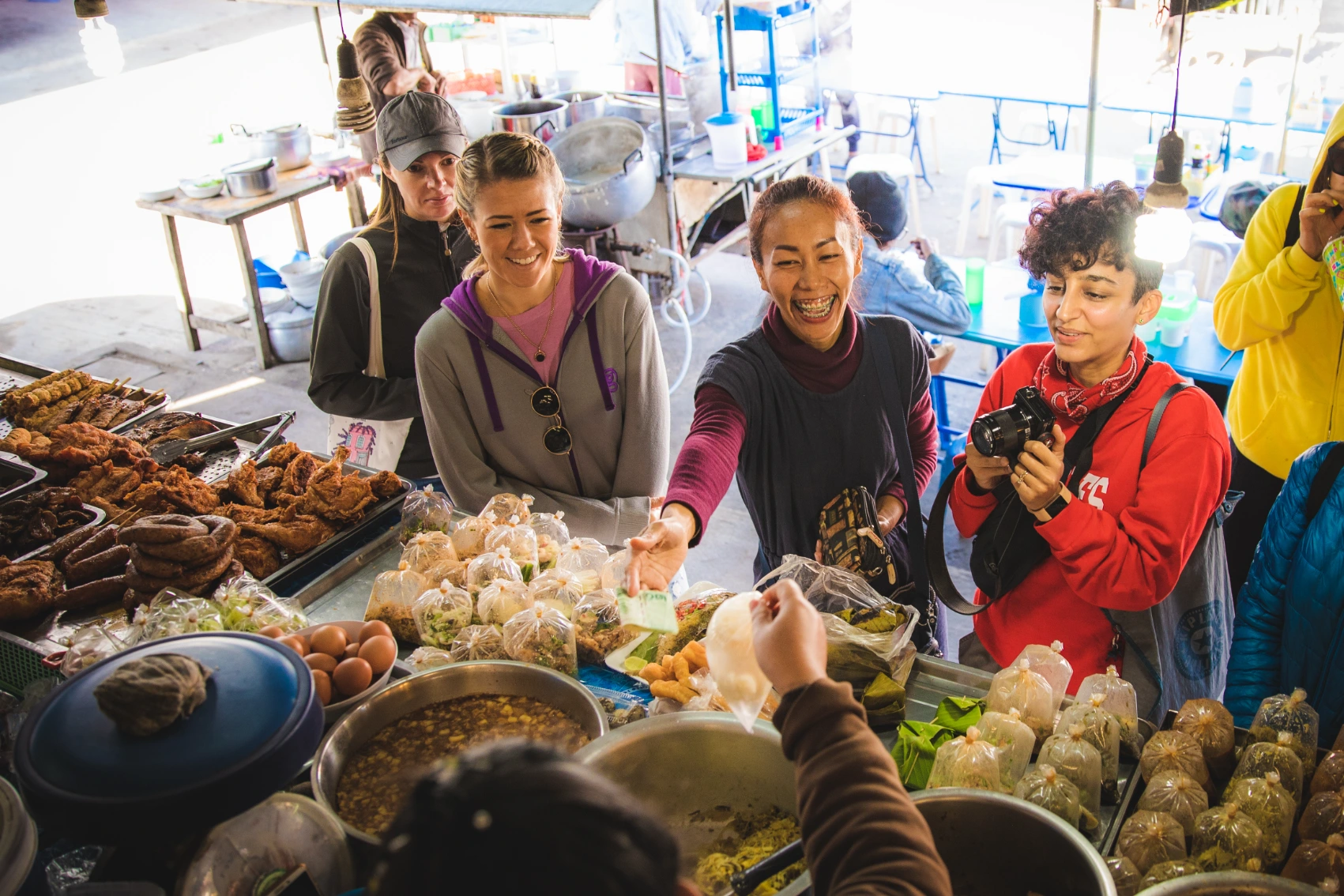 A group of travellers buys food at a market in Thailand