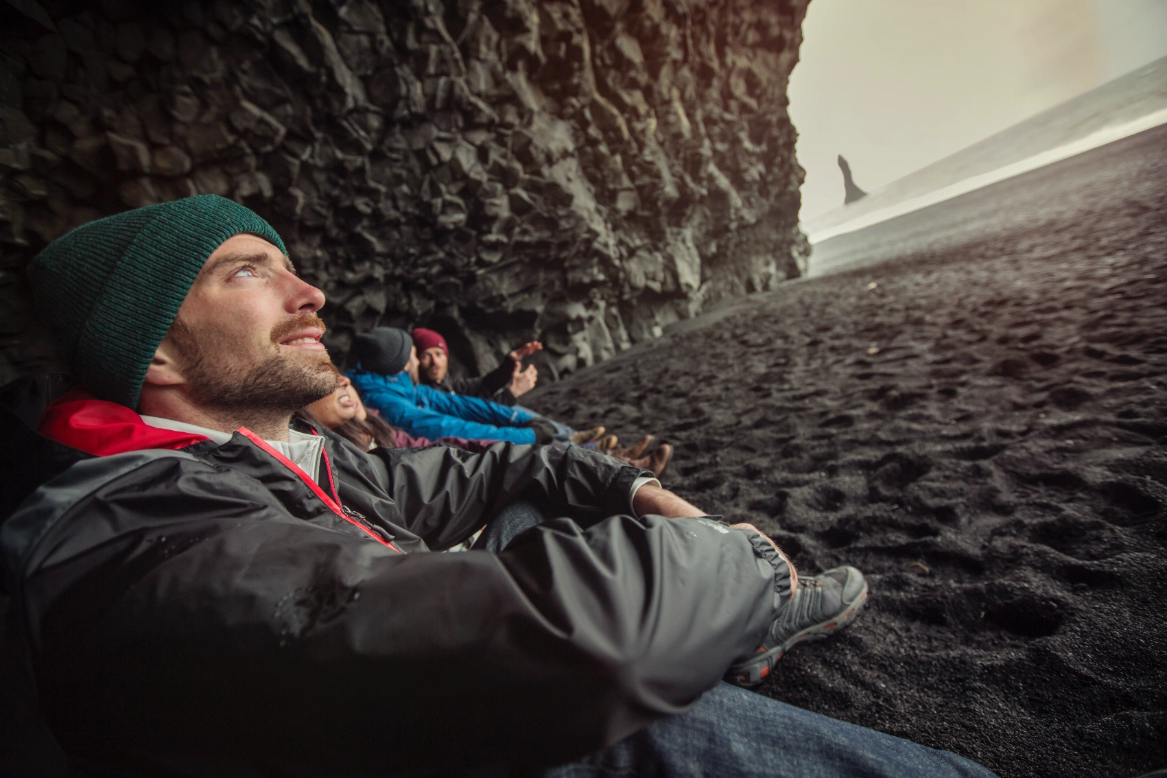 A male traveller sits in a cave with friends in Iceland