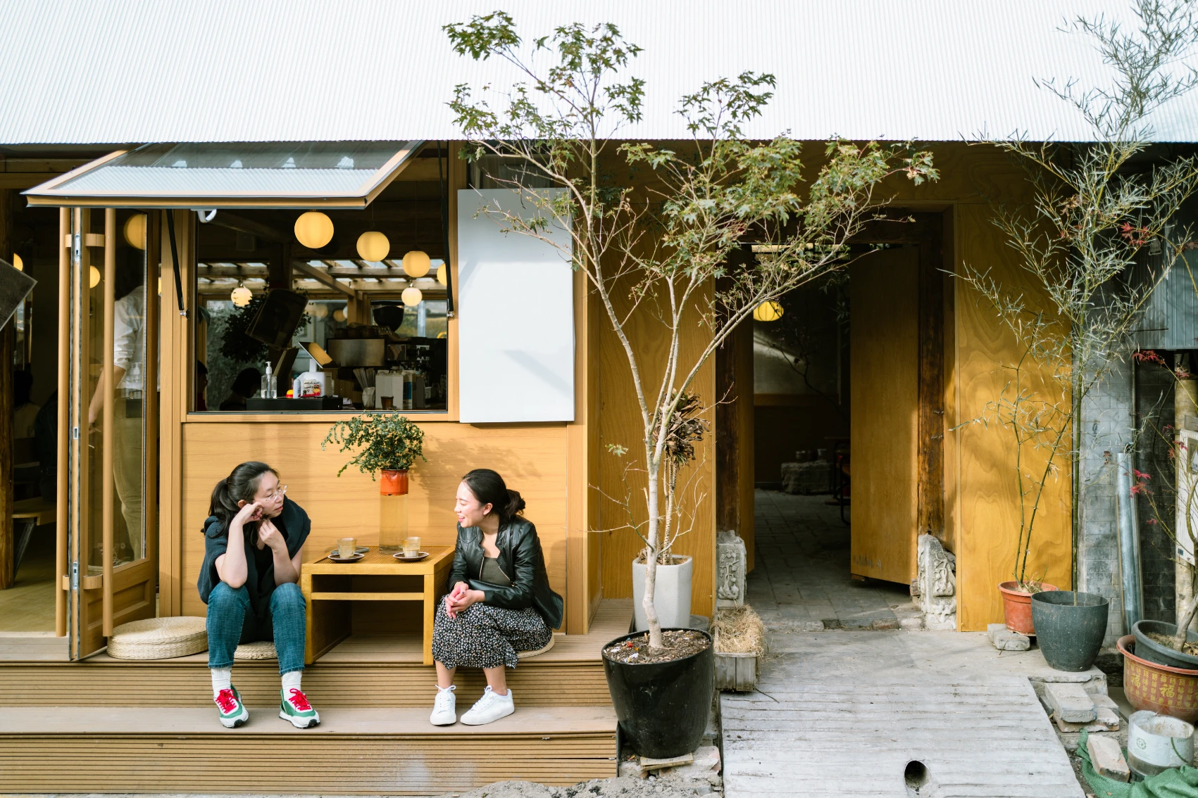 Two travellers sit outside a small business in a hutong alleyway in Beijing, China