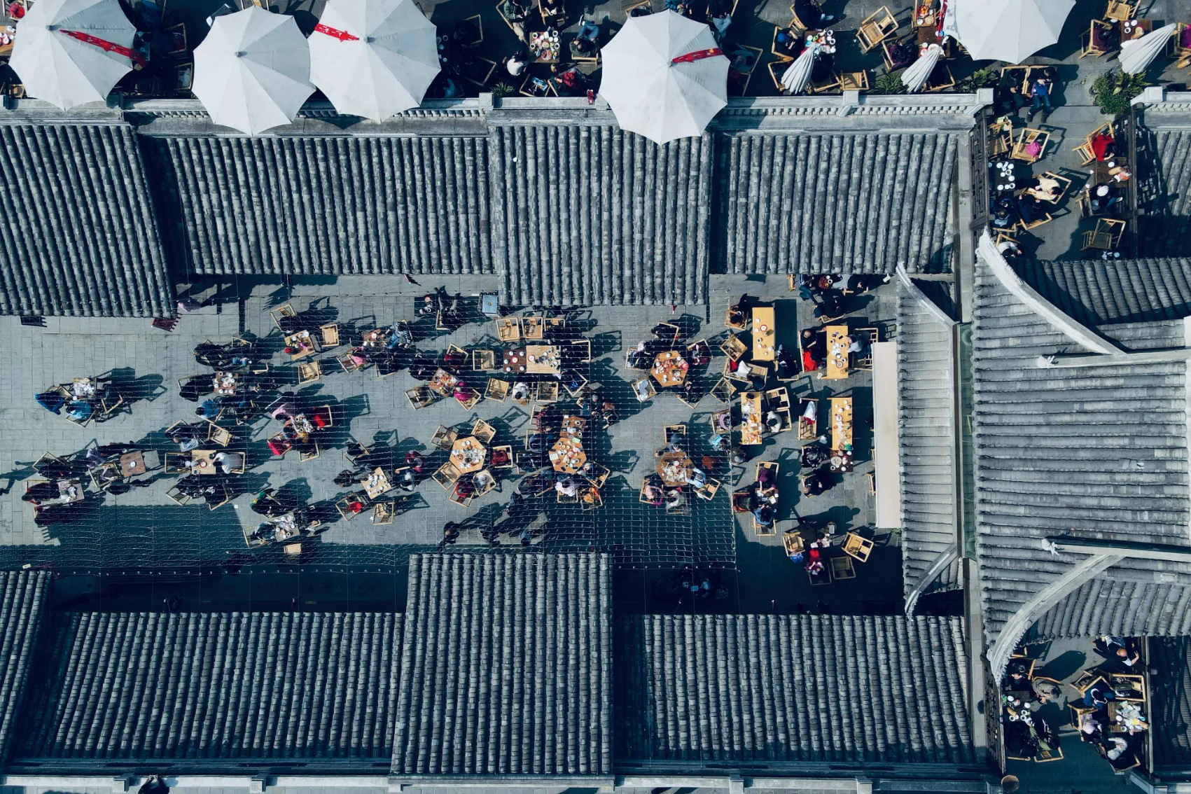 Aerial view of teahouse roofs and a courtyard of people drinking tea in Chengdu, China