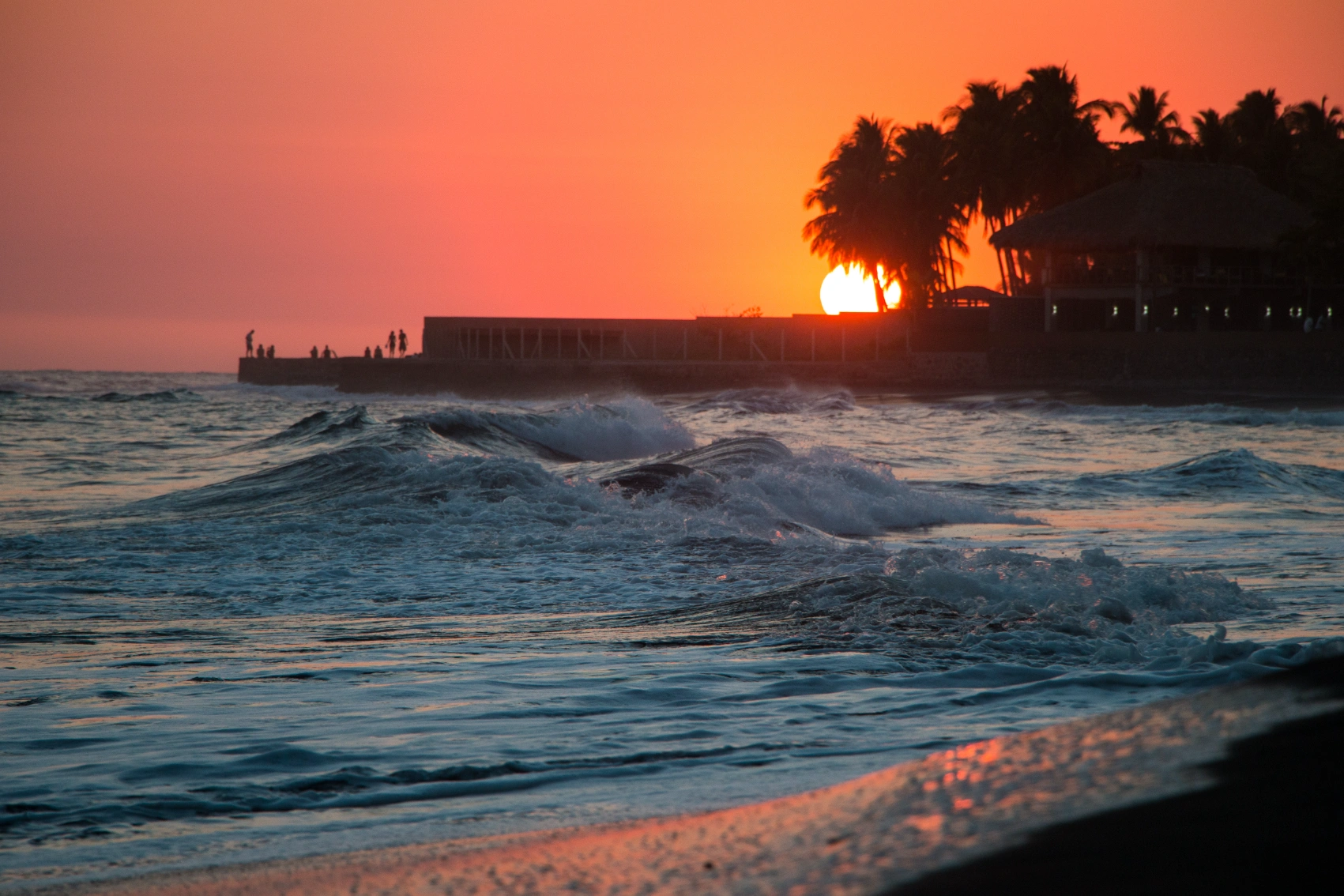 El Tunco, El Salvador Sunset view of El Tunco beach, with silouhetted people walking on a dock, El Salvador