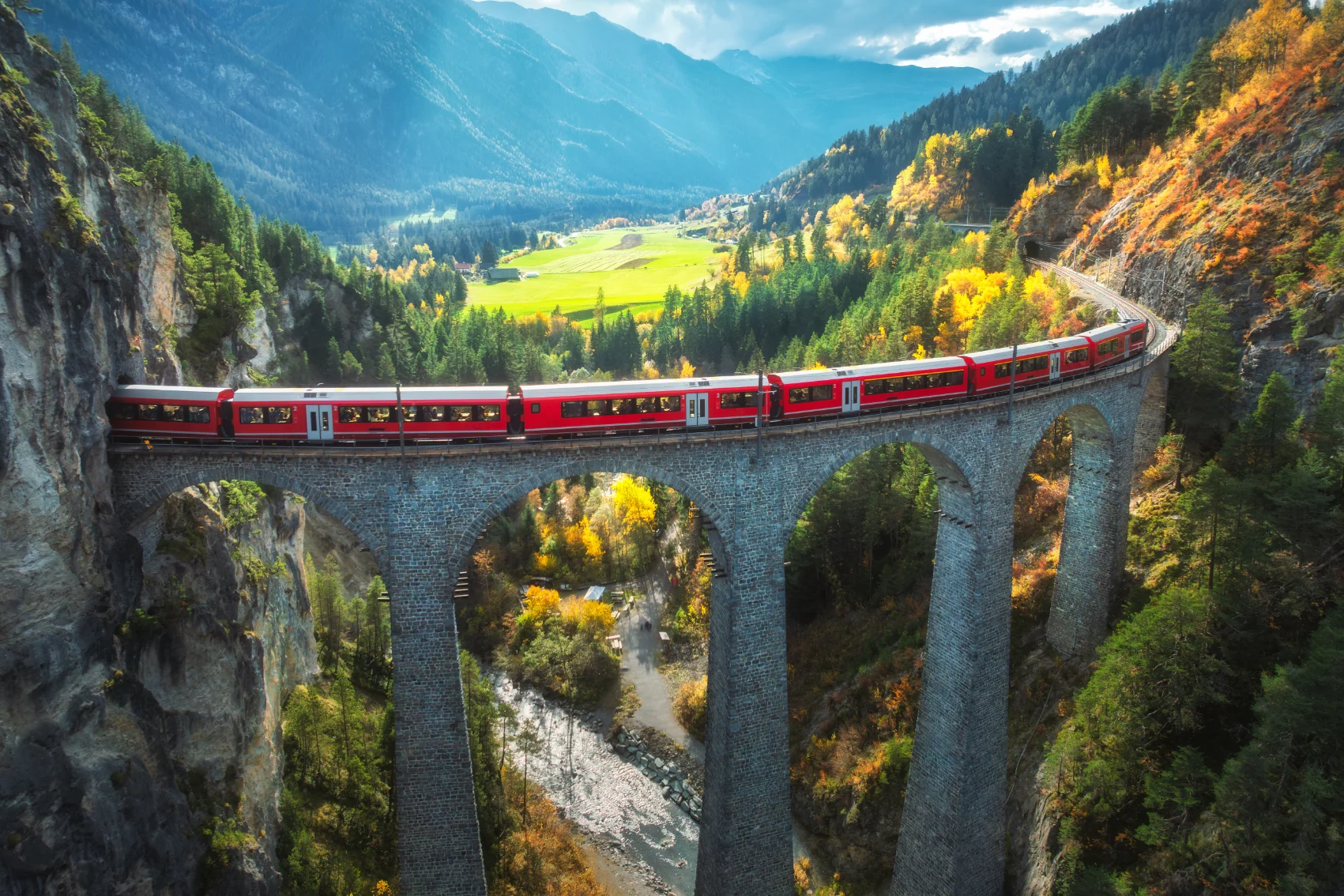 Aerial view of a red Bernina Express train on a viaduct in Switzerland