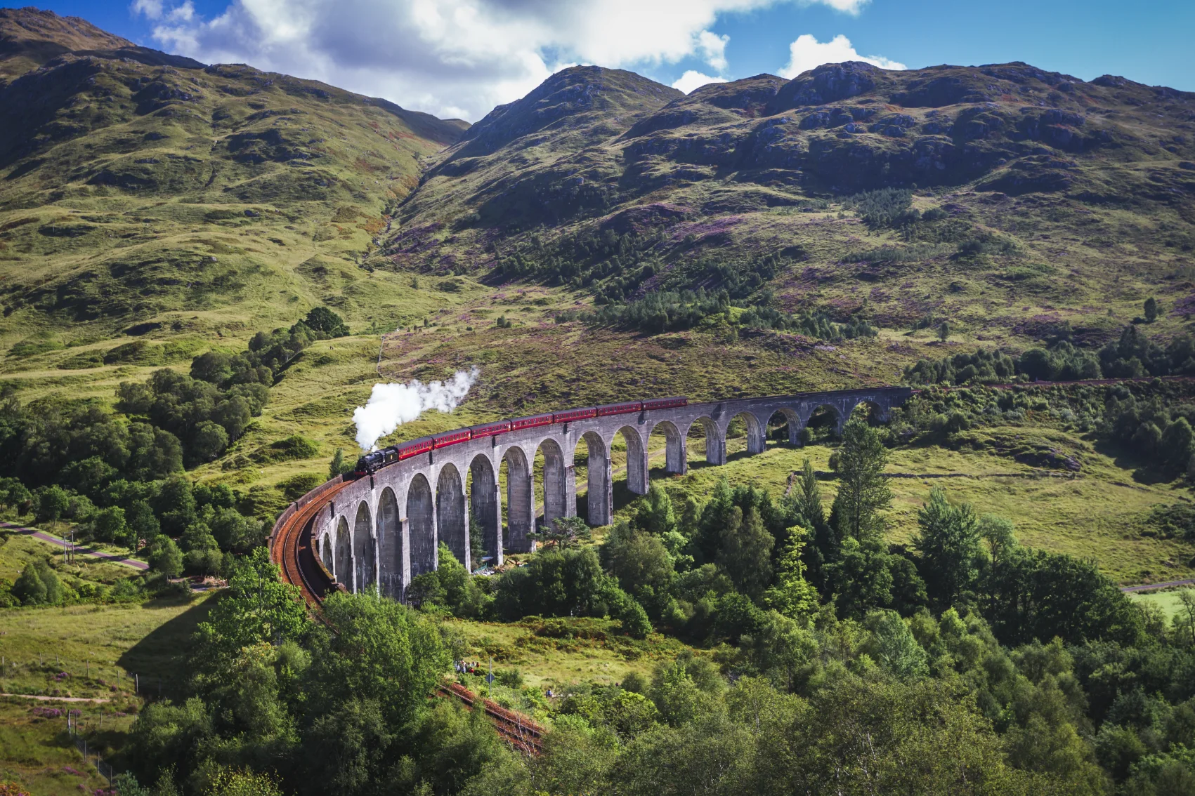 Steam train on the Glenfinnan Viaduct with the highlands of Scotland in the background