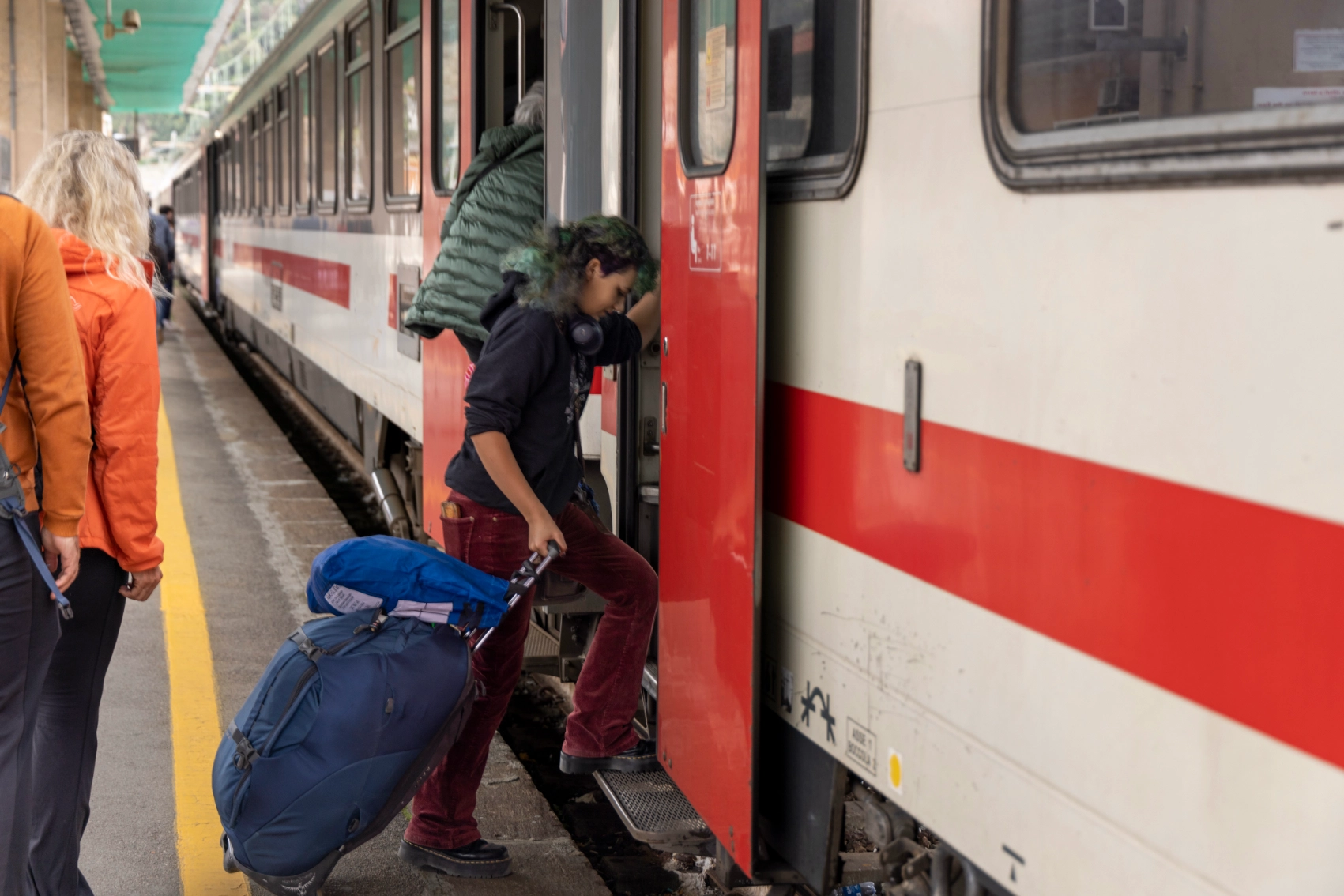 A woman traveller boards a train with her luggage in Italy