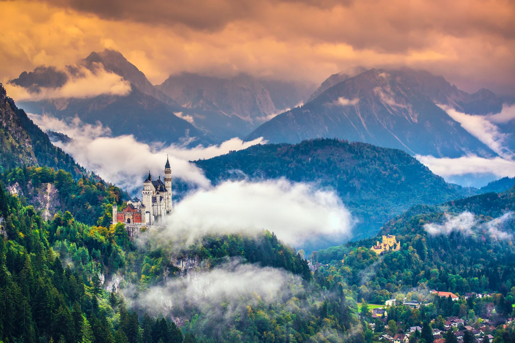 Neuschwanstein Castle in the mountains with low-hanging clouds in Germany