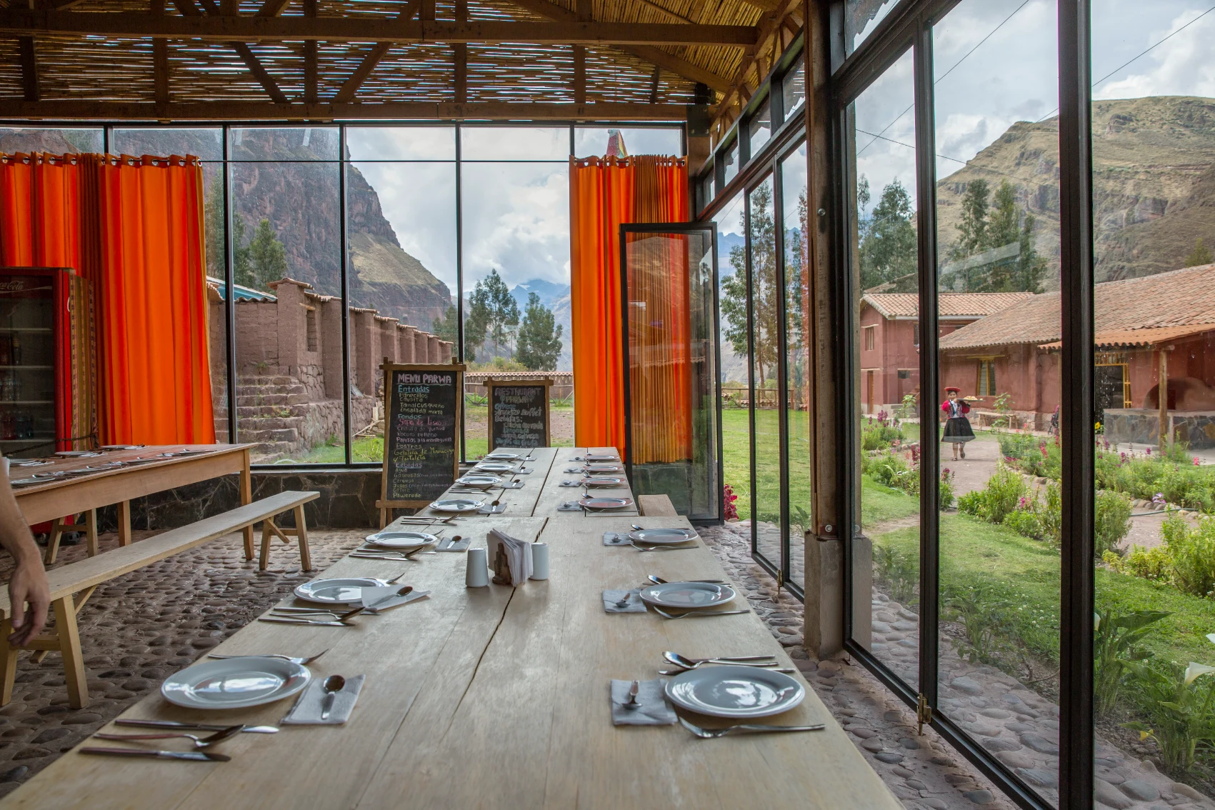 Parwa Community Restaurant, Peru Tables at Parwa Community Restaurant set inside glass walls overlooking a mountainous landscape in Peru