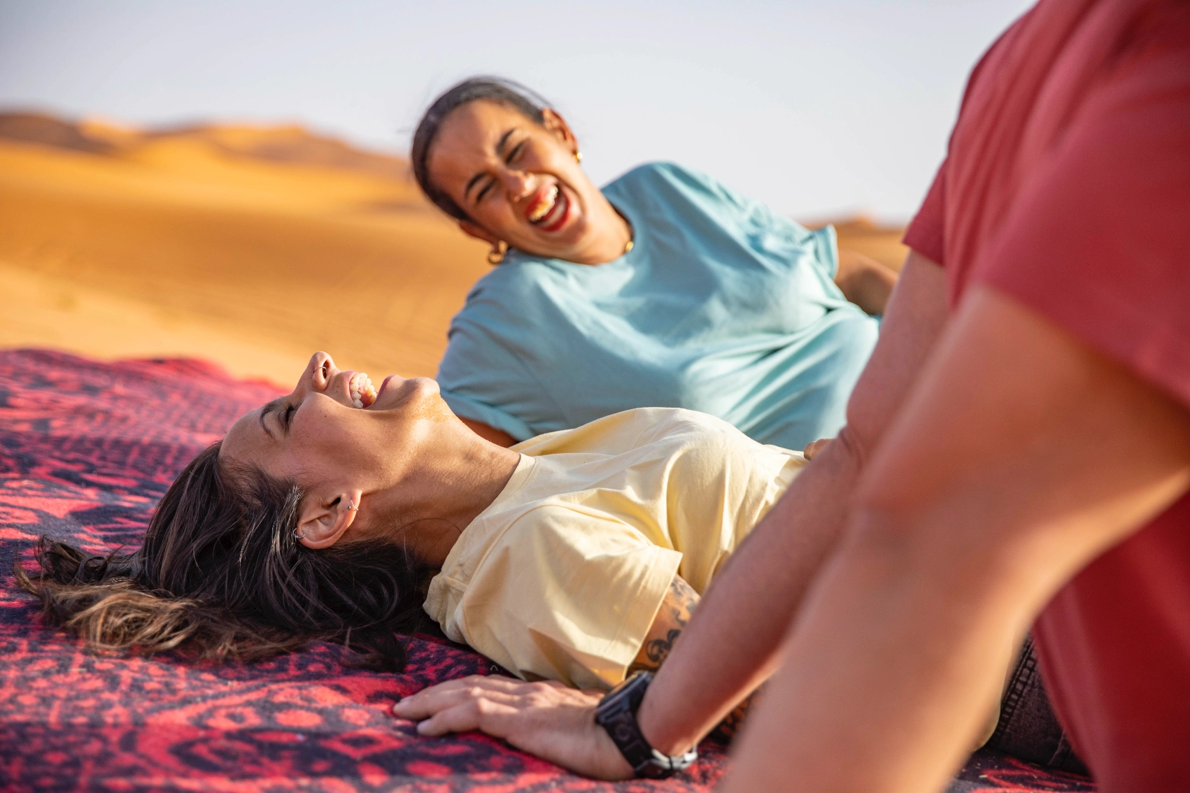 A group of travellers laughs on a dune in Morocco