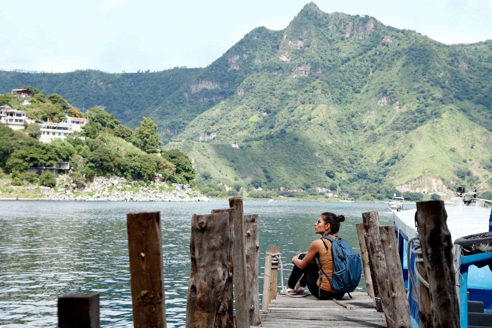 Lake Atitlán, Guatemala A female traveller wearing a backpack sits at a dock overlooking Lake Atitlán, Guatemala
