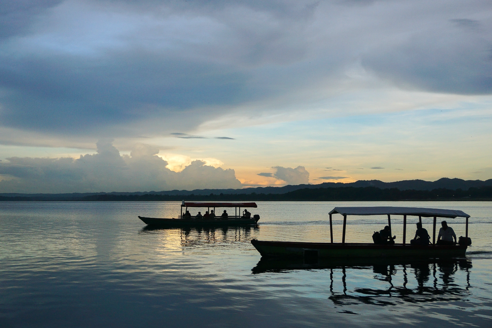 Flores, Guatemala Two groups of silhoutetted travellers ride boats to Flores, Guatemala