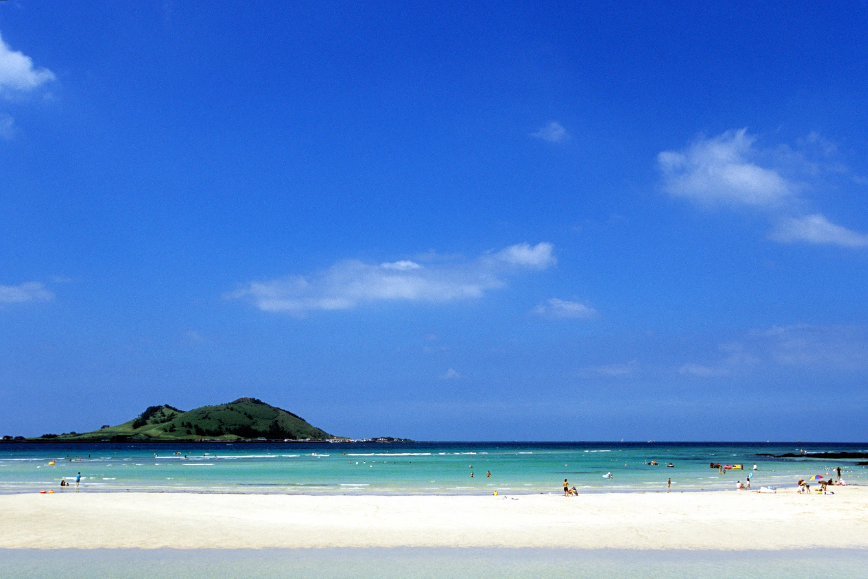 People play and relax on a white-sand beach on Jeju Island, South Korea