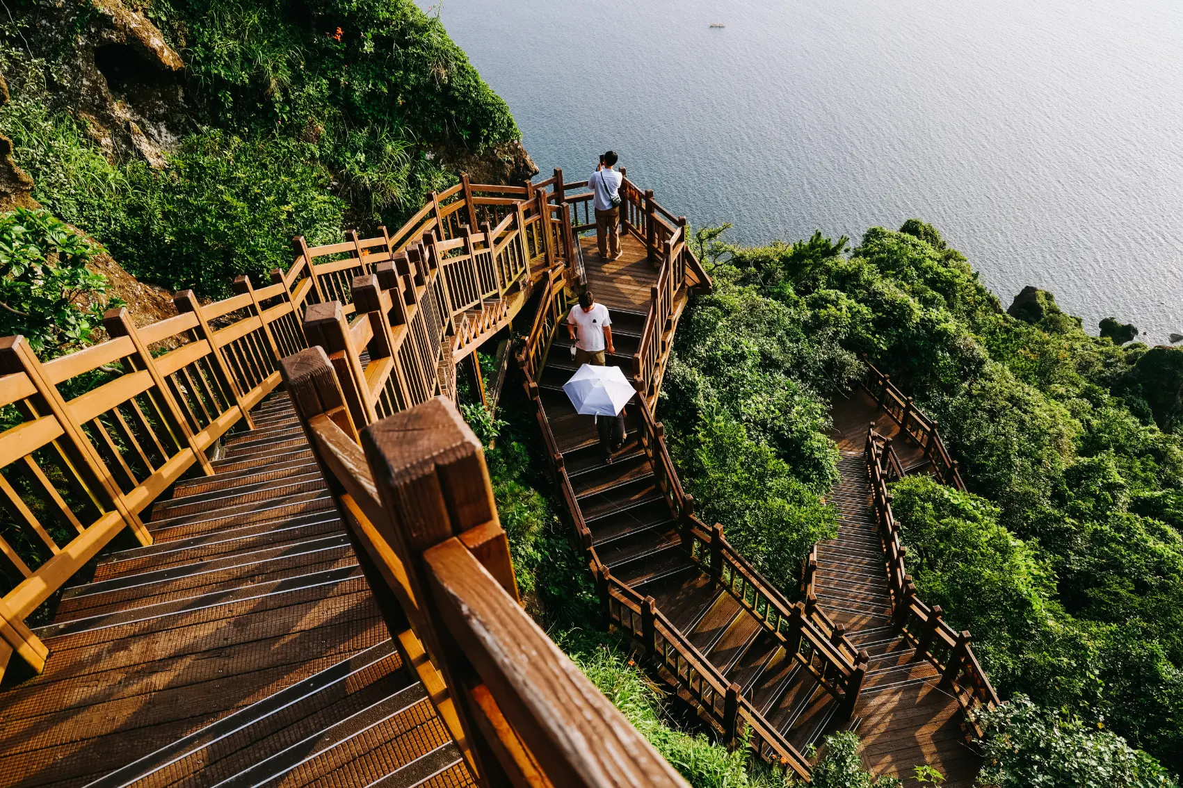 People stop to take photos and walk down the stairs that climb Seongsan Mountain in Jeju Island, South Korea